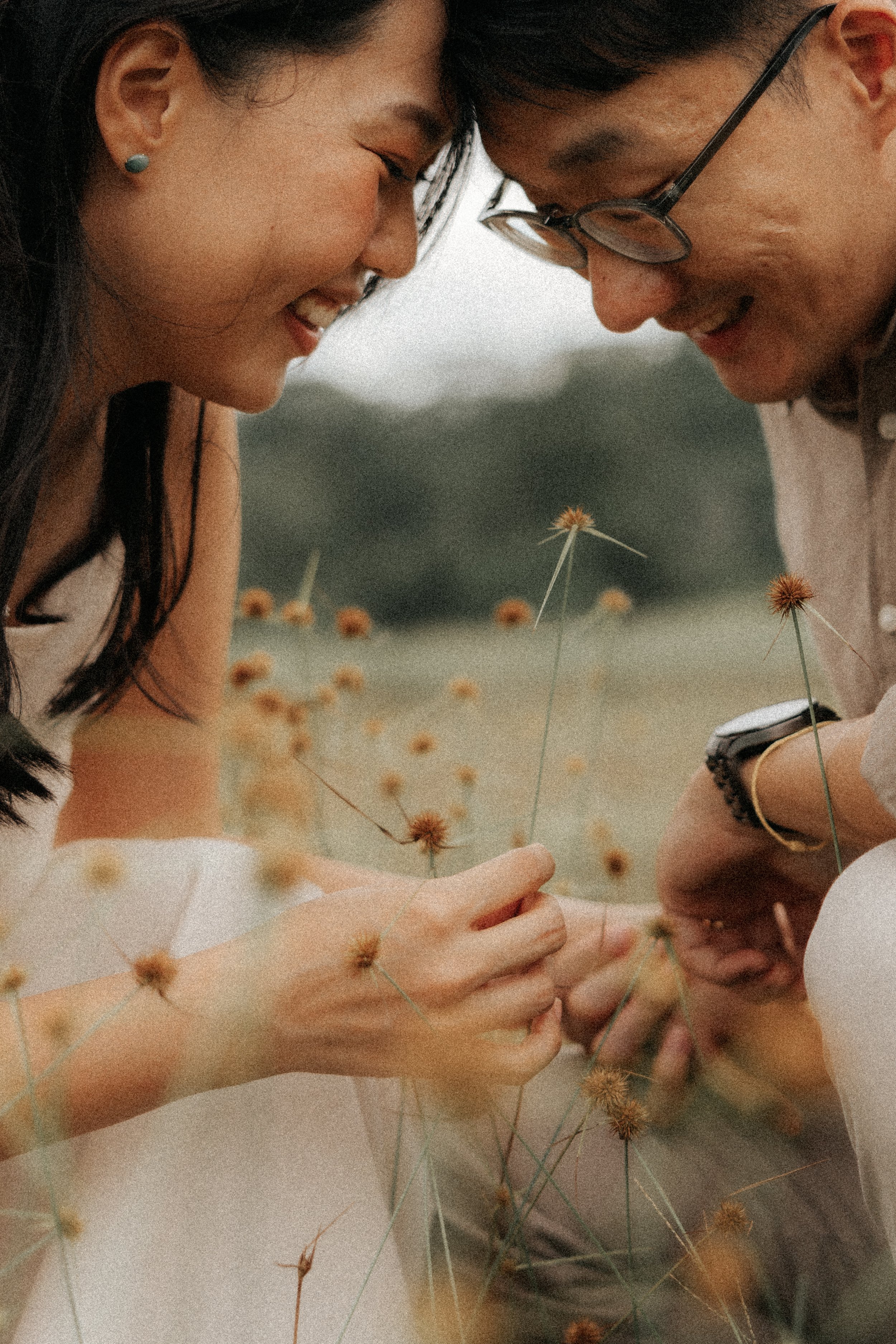 Playful pre-wedding photo of a couple sharing a moment among wildflowers at East Coast Park, captured by Breadandbutterworks in a soft and heartfelt style.