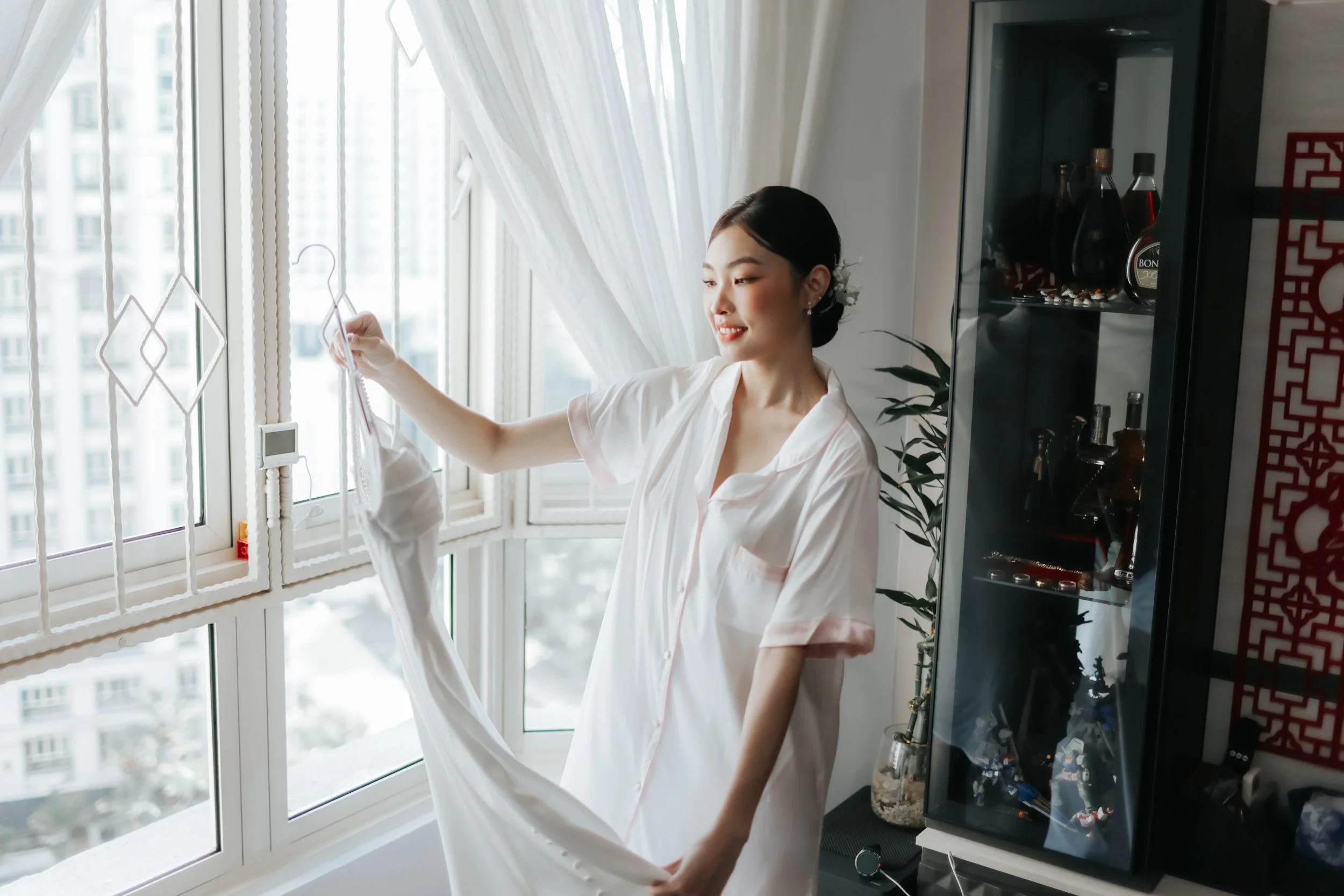 Light and airy actual day wedding photoshoot in Singapore, the bride is admiring her wedding gown at home before the wedding. Captured by Arielle from Breadandbutterworks.