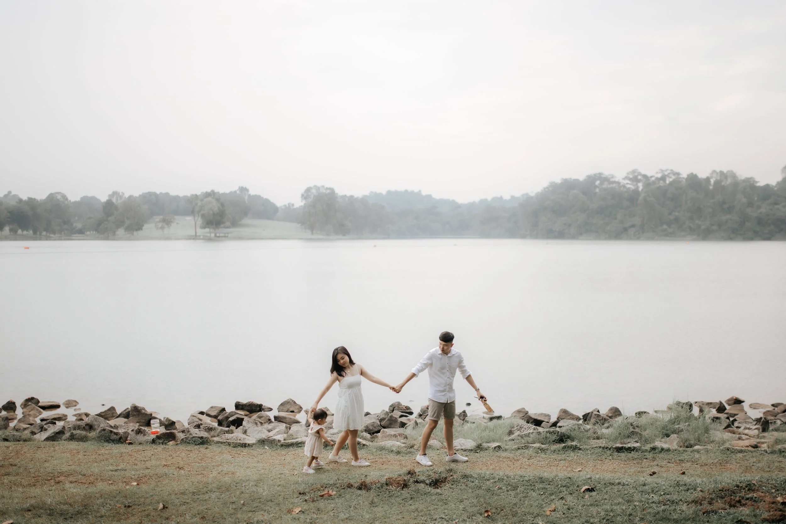 Light and airy family photo of a young family strolling through Lower Peirce Reservoir, captured in a soft outdoor setting in Singapore.
