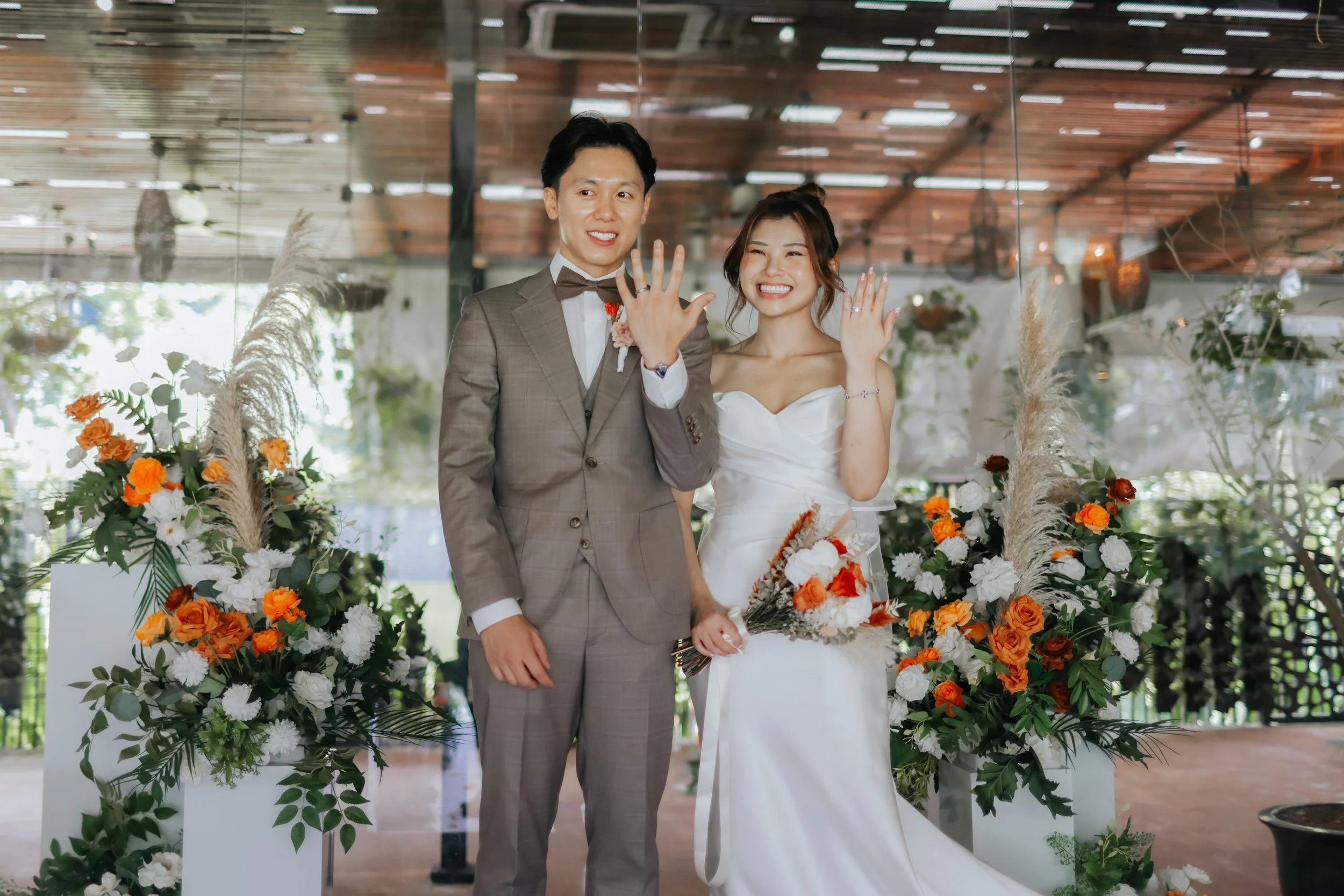 Light and airy actual day wedding photoshoot at Canopy HortPark, the couple shows off their wedding bands to their guests. Captured by Arielle from Breadandbutterworks.