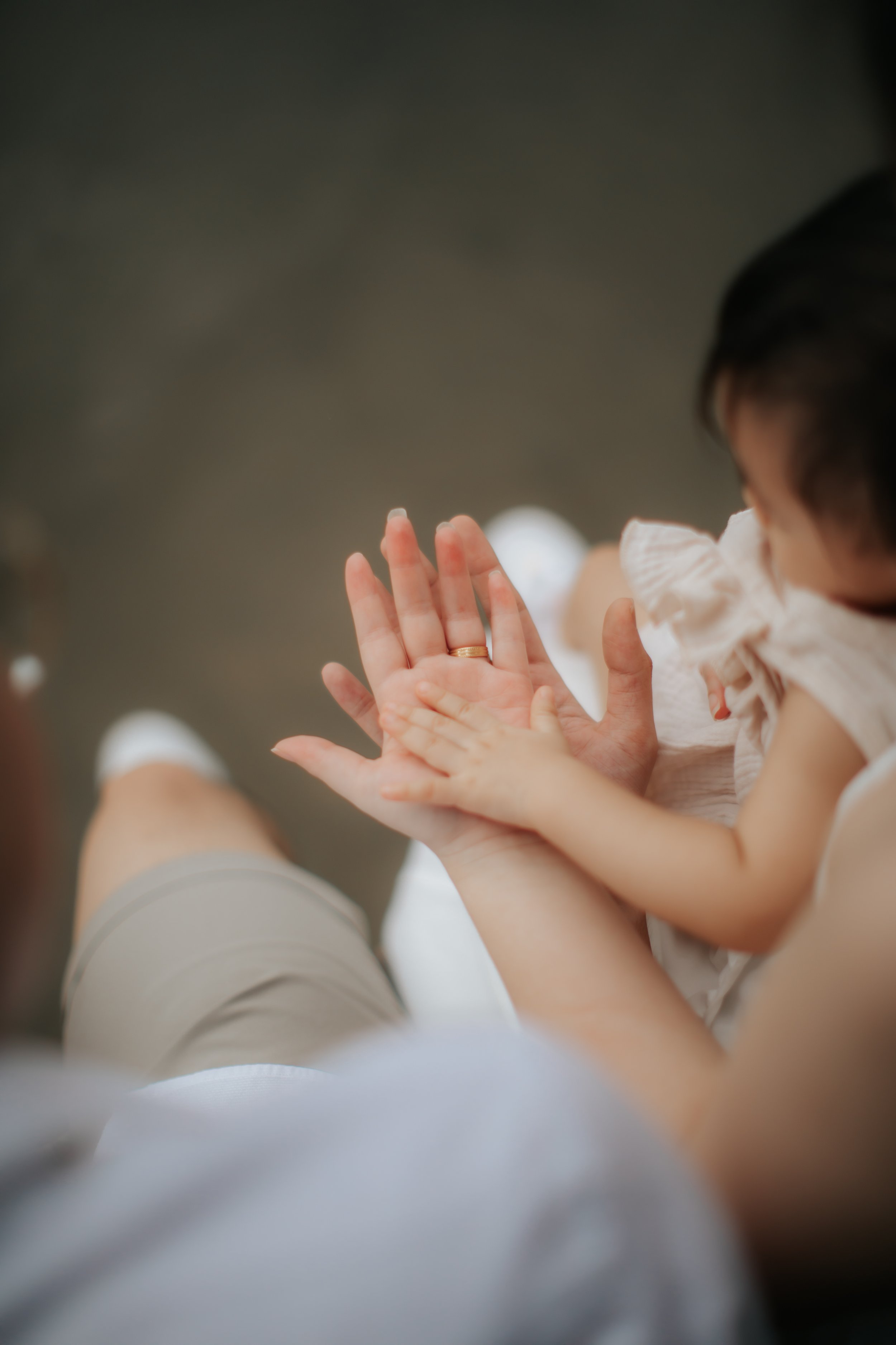 Light and airy cinematic family photo of a young family stacking hands, captured in a soft outdoor setting in Singapore.