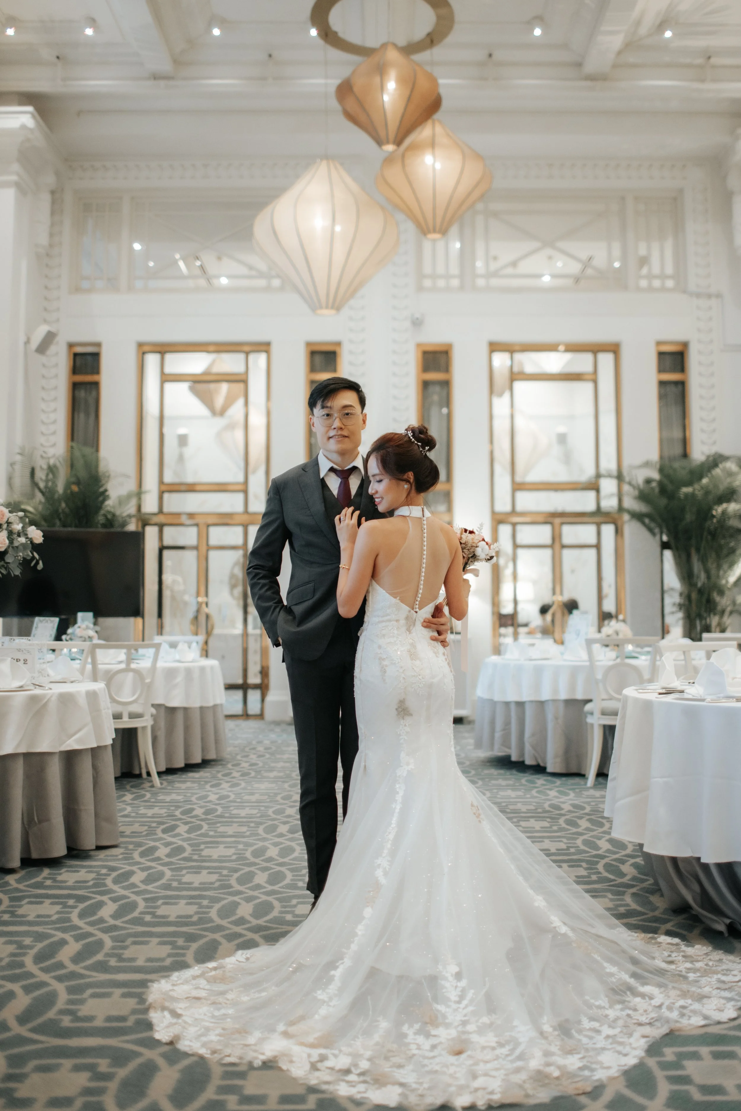 Light and airy actual day wedding photography of the bride and groom posing in their wedding venue at Fullerton Hotel. Captured by Arielle for Breadandbutterworks.
