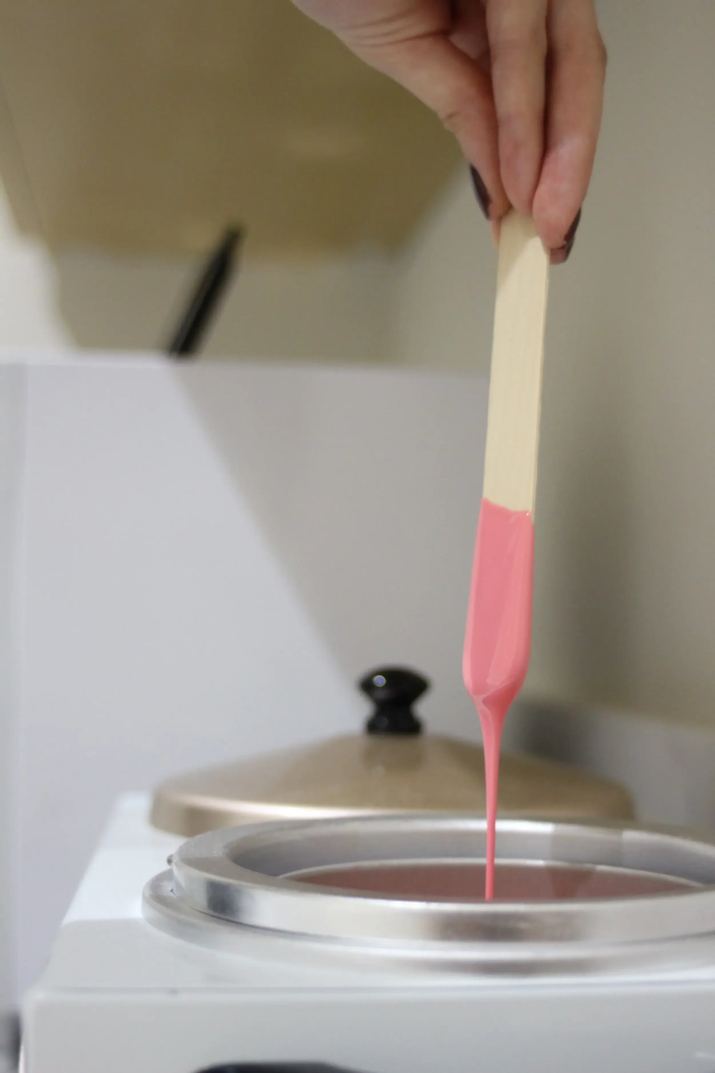 Licensed esthetician preparing for waxing service with pink wax in La Quinta, CA