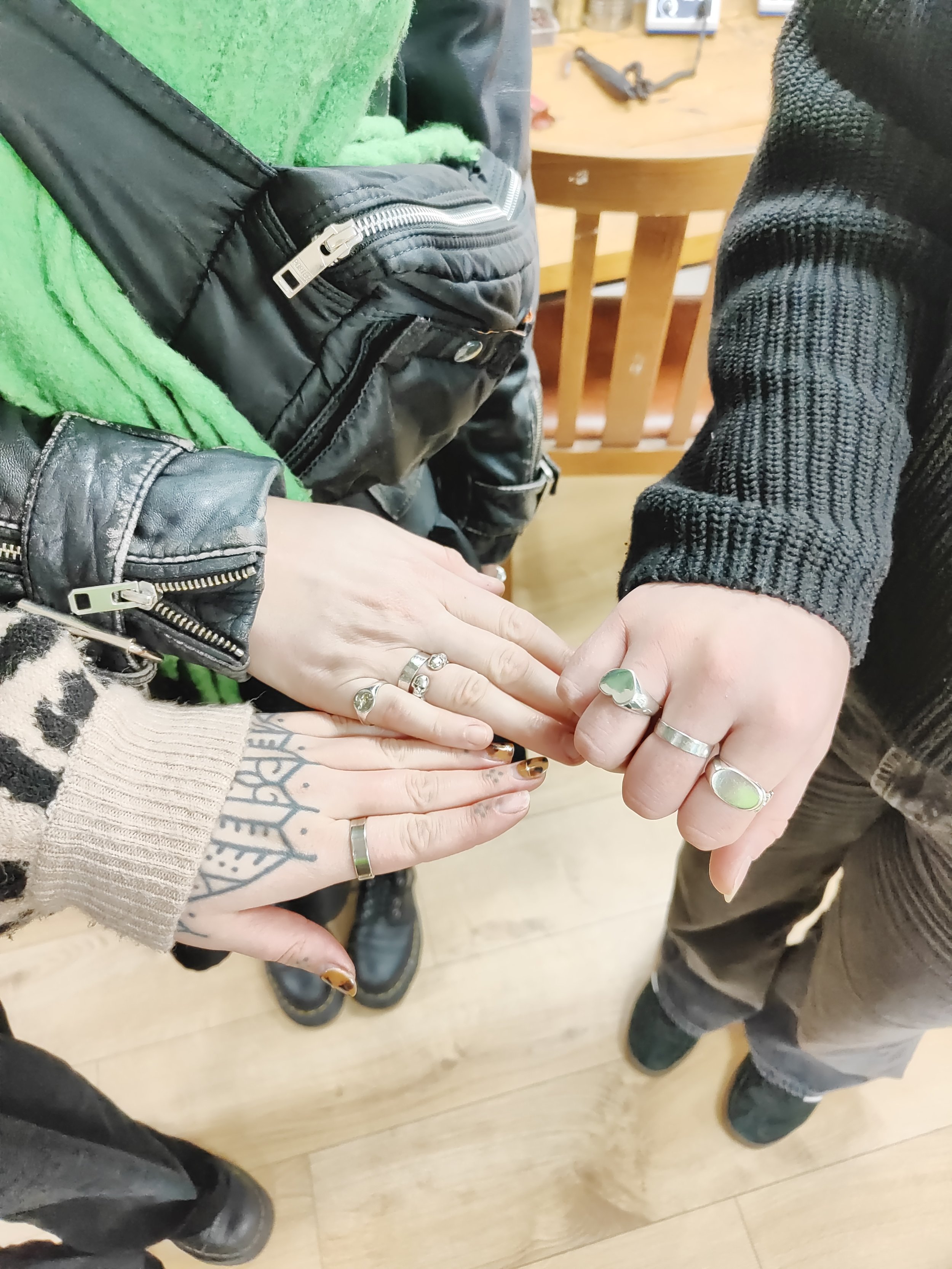 The hands of three people show handmade silver rings made during a beginners ring making workshop with Silver & Steel.