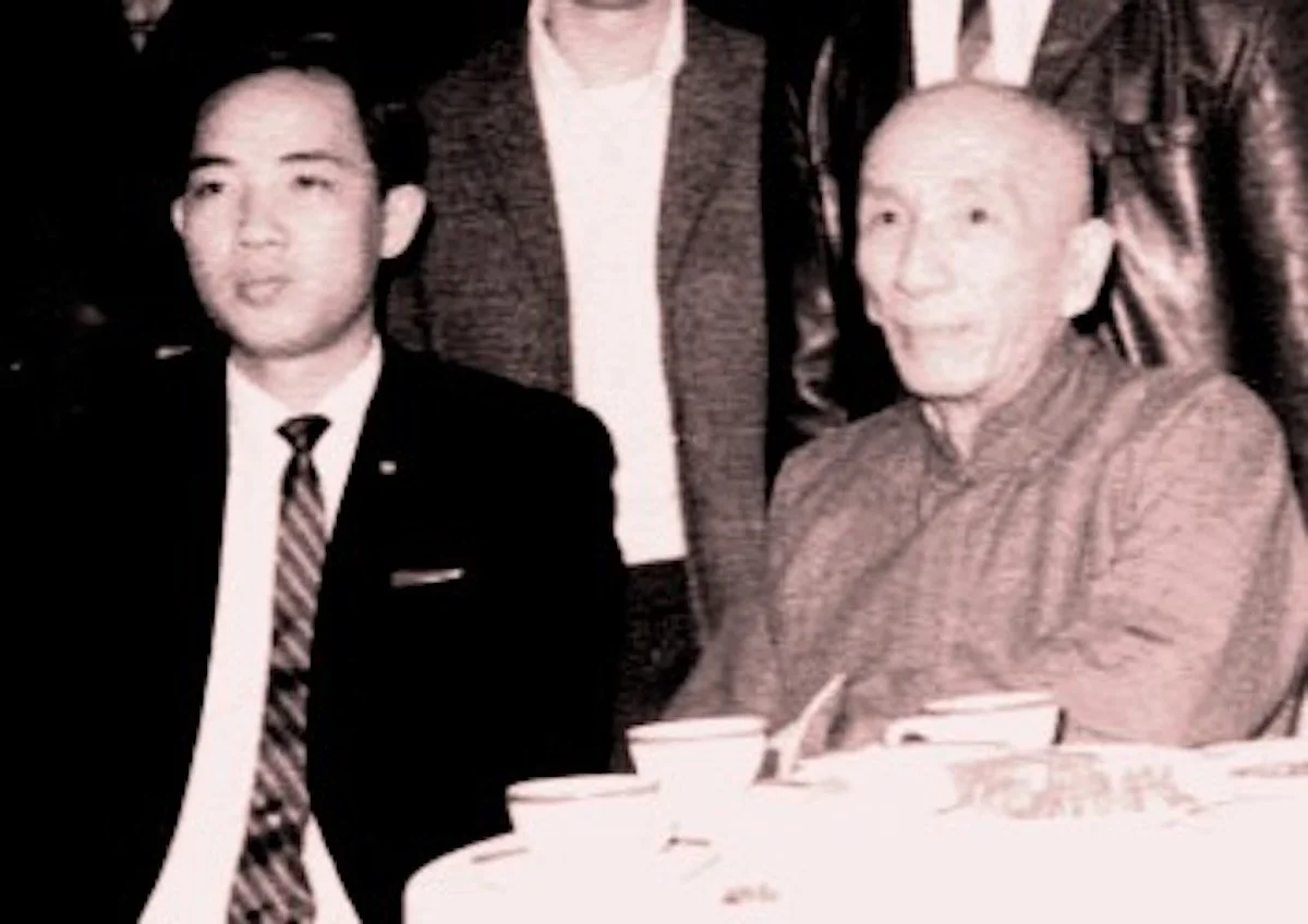 Informal photo of Grandmaster Yip Man seated at a table during a formal group dinner event with his disciple, Moy Yat, sitting at his right hand.