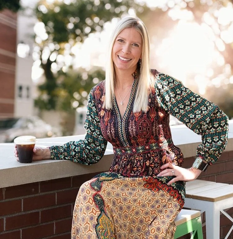 Amy Schamberg smiling and holding a cup of coffee
