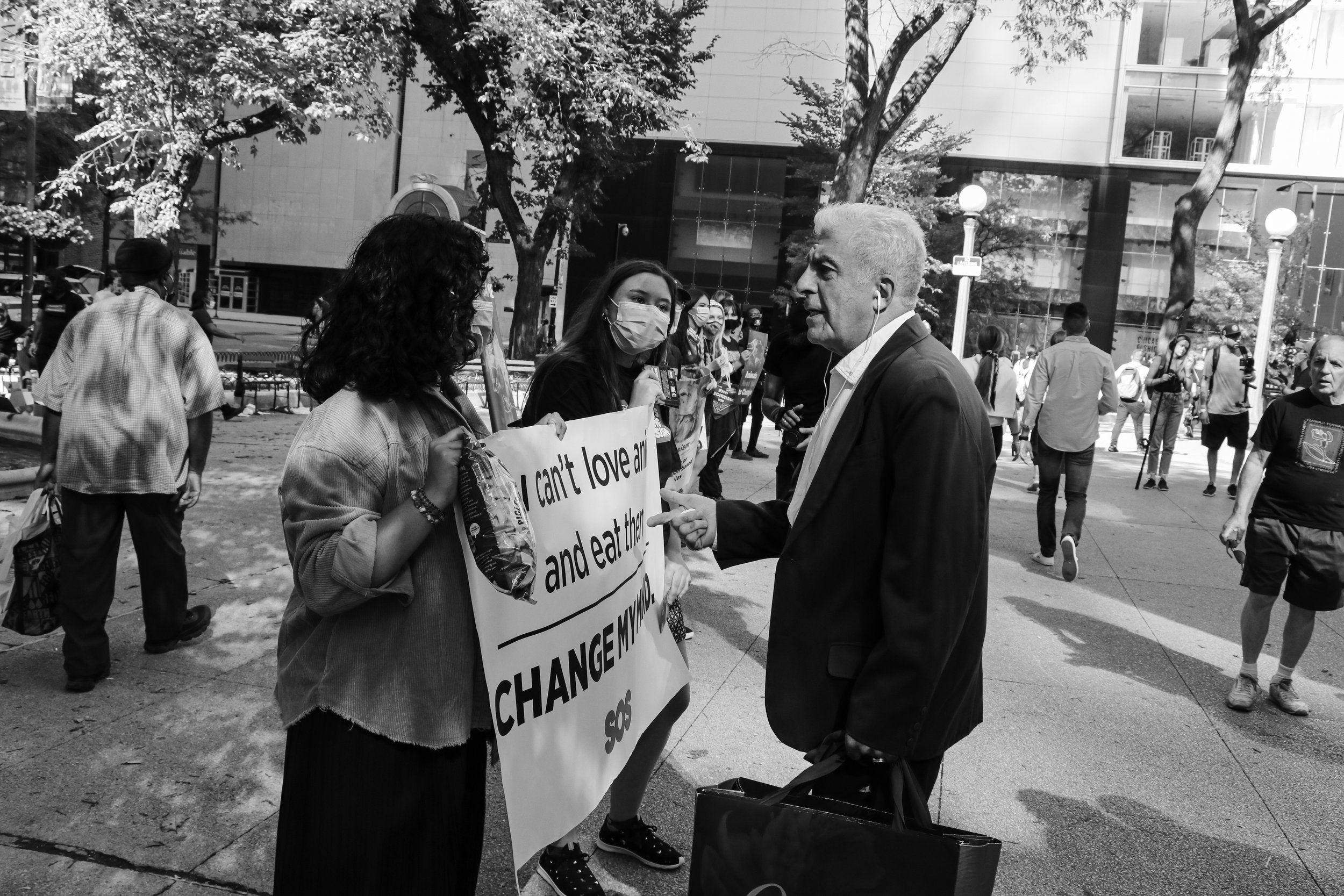 A white-haired man dressed in a polished suit approaches the sign reading “I can’t love animals and eat them too. Change my mind.” He reveals that he is a vegan himself, and endorses the protestors for showing up and raising their voice.