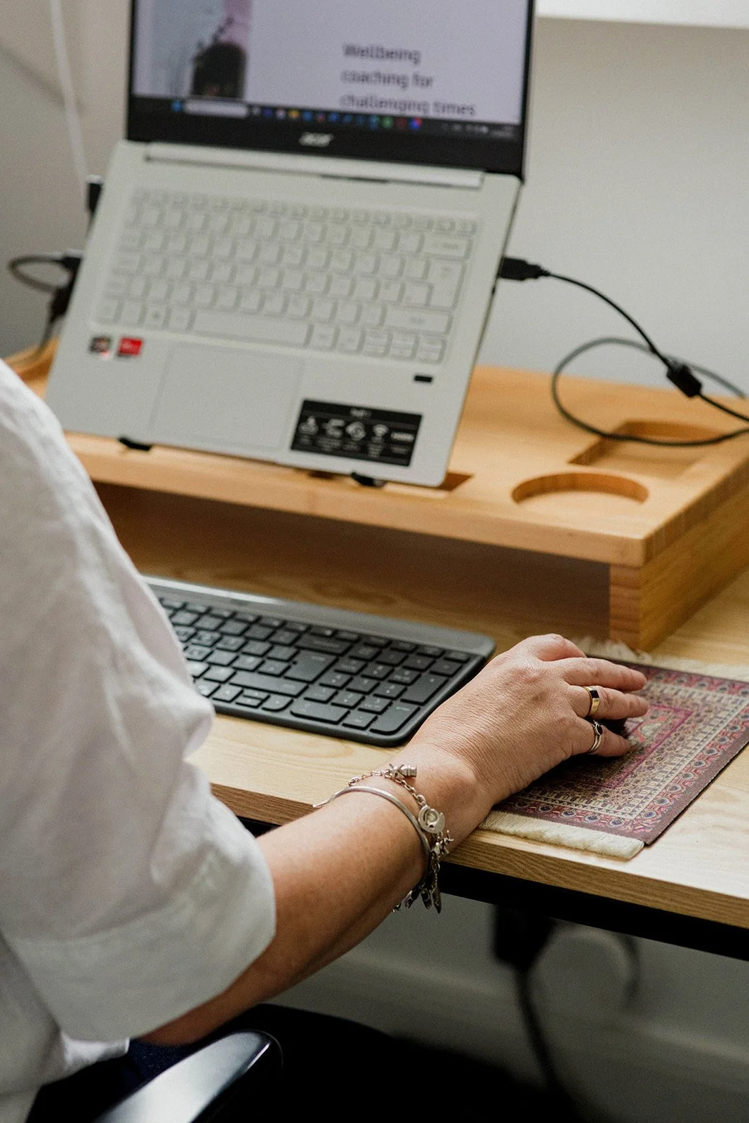 Sam is sitting down at her desk coaching. The image is of her wrist and hand moving the lap top mouse.