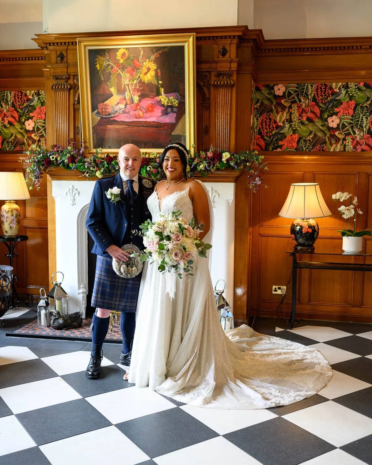 A beautifully relaxed wedding portrait at Lochgreen House Hotel in Troon. The bride and groom stand together in front of the elegant fireplace, surrounded by warm wood panelling and floral details. A timeless moment captured in one of Ayrshire’s most