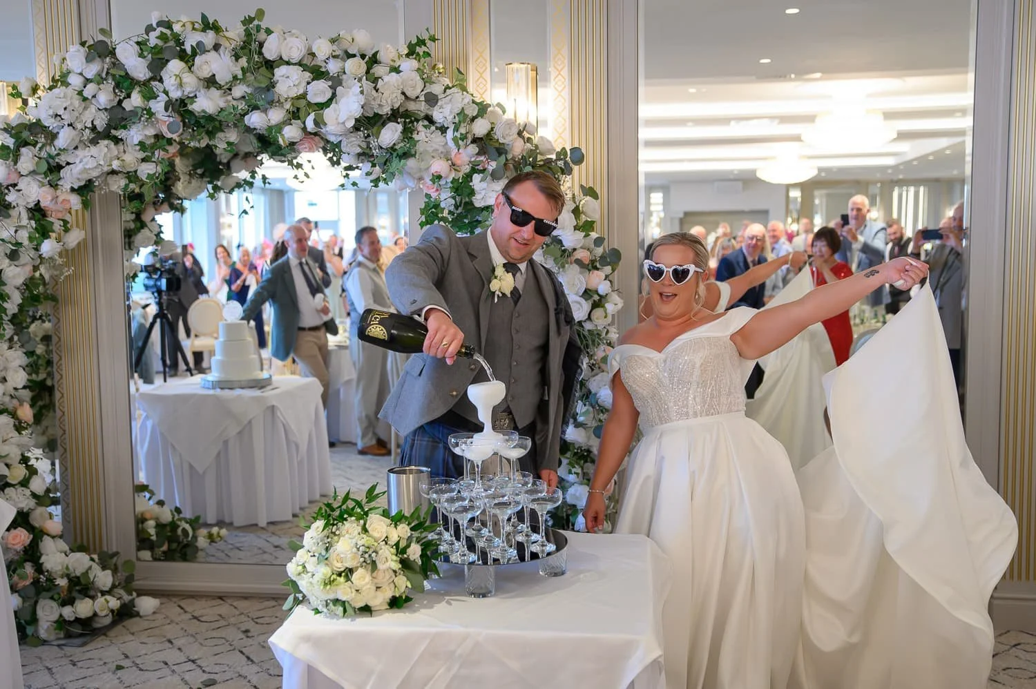 Bride and groom pouring champagne into a champagne tower before the speeches at their wedding at Seamill Hydro Hotel in West Kilbride.