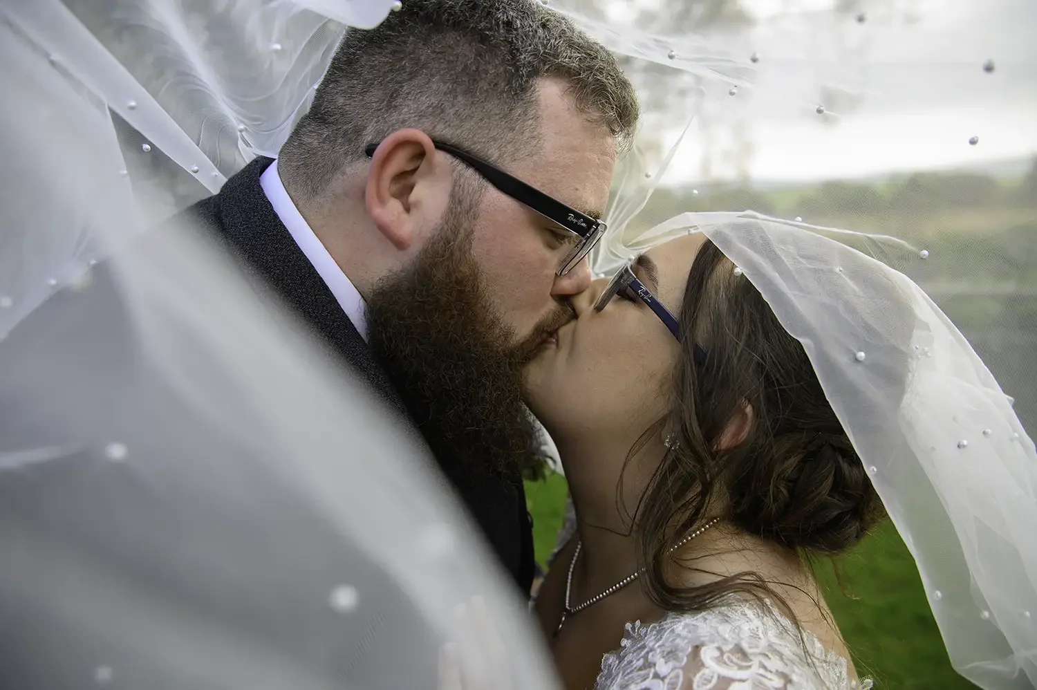 Close up of bride and groom kissing under veil at Dalduff Farm in Maybole