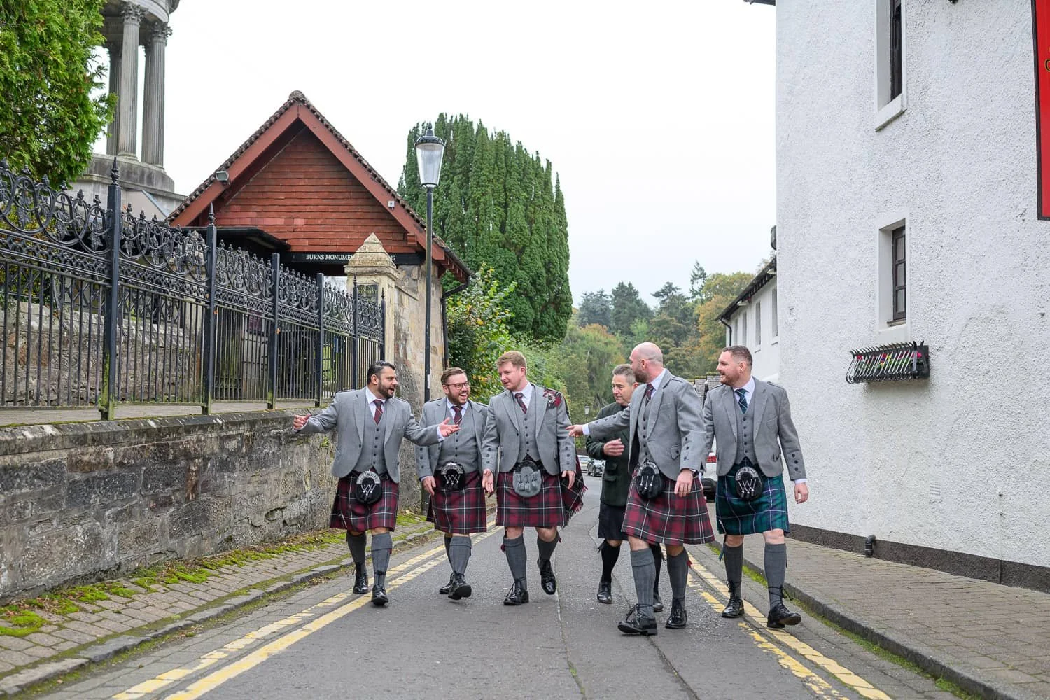 Groom and groomsmen walking together in kilts near Brig O'Doon House Hotel in Alloway Ayr before the wedding ceremony