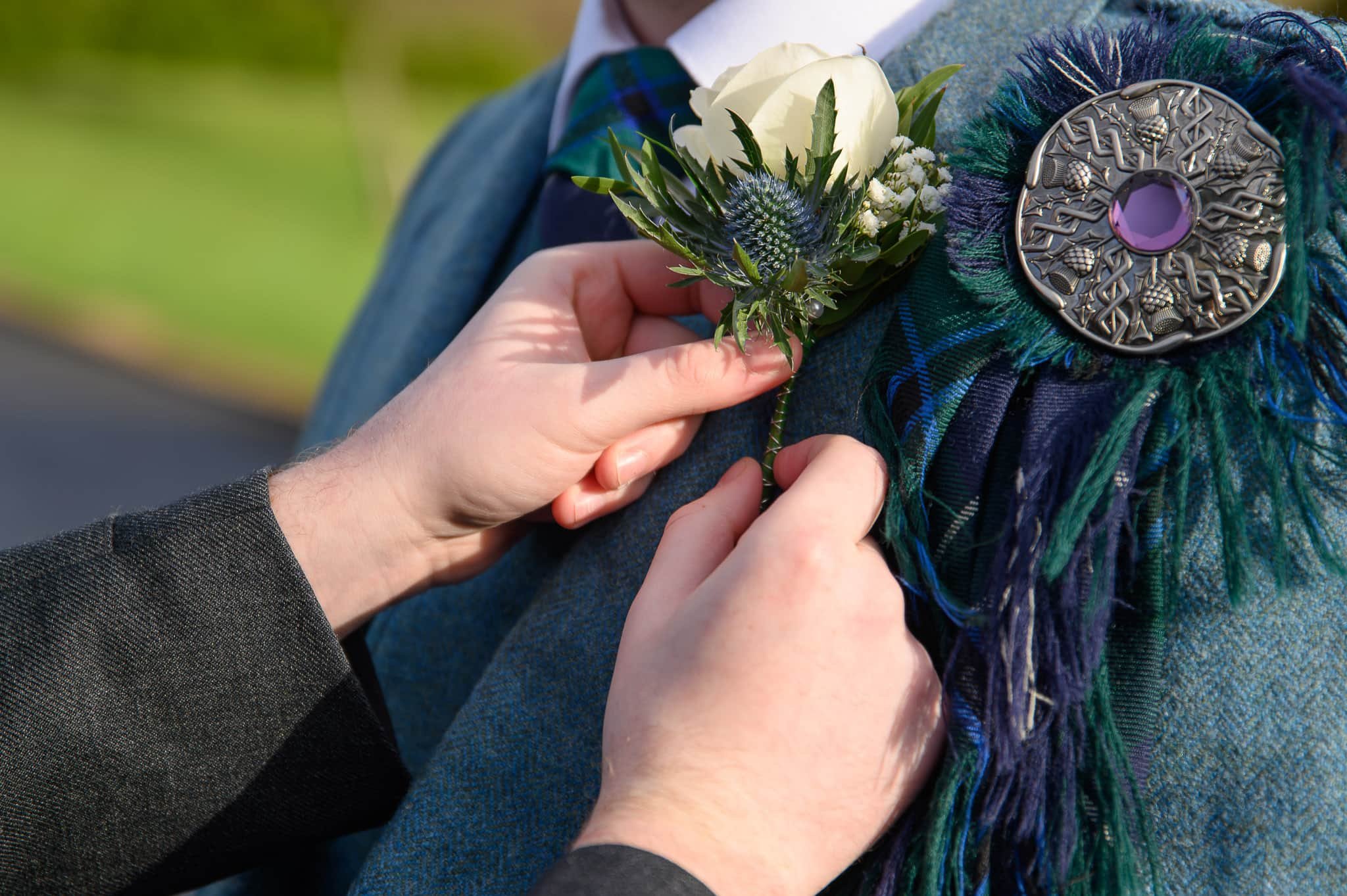 Close up of the groom’s buttonhole being adjusted during morning preparations at Lochside House Hotel in New Cumnock