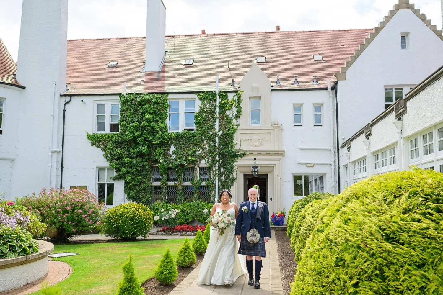 Bride and groom walking in front of Lochgreen House Hotel in Troon, Ayrshire