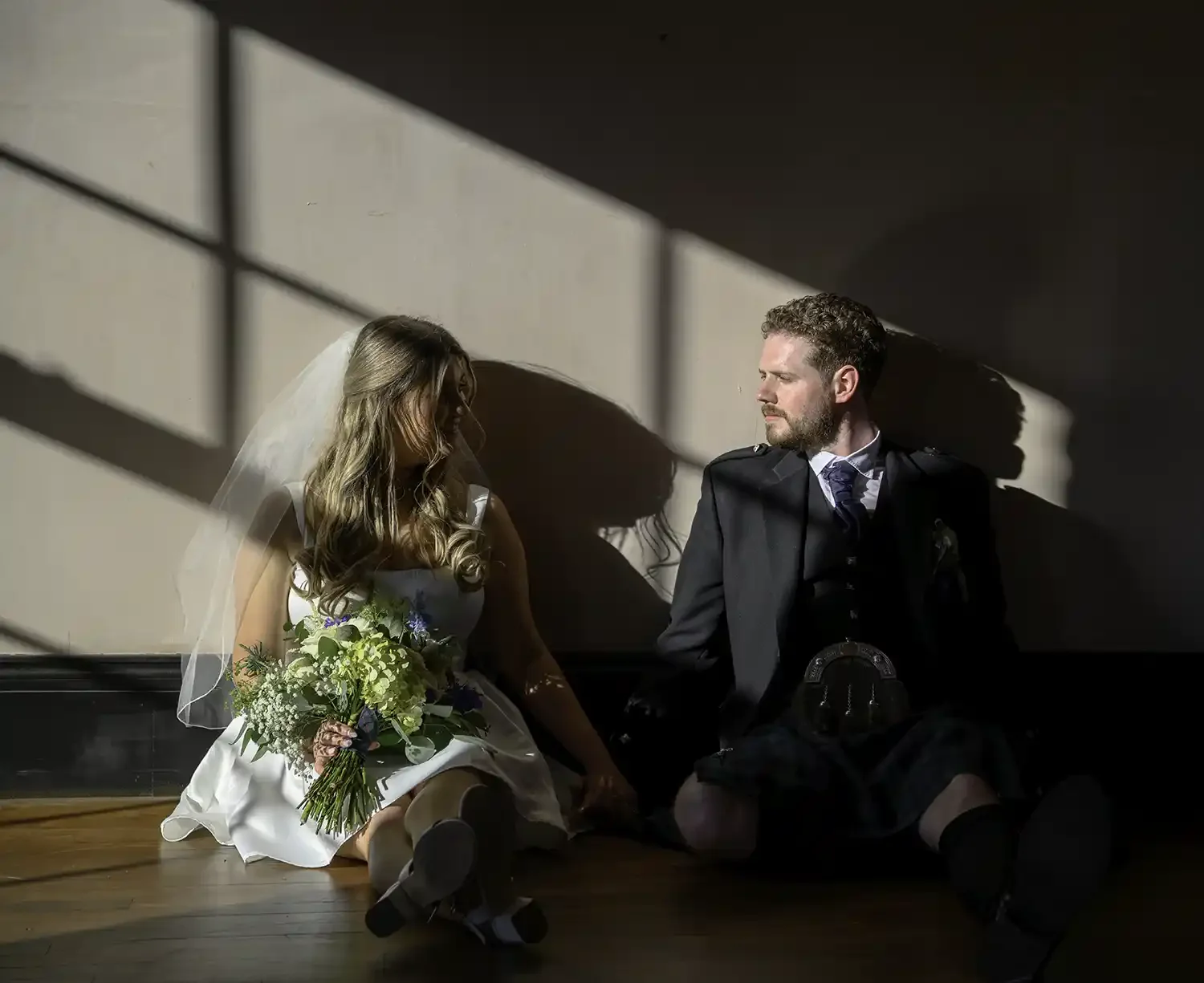 Bride and groom sitting together in window light at The Engine Works in Glasgow