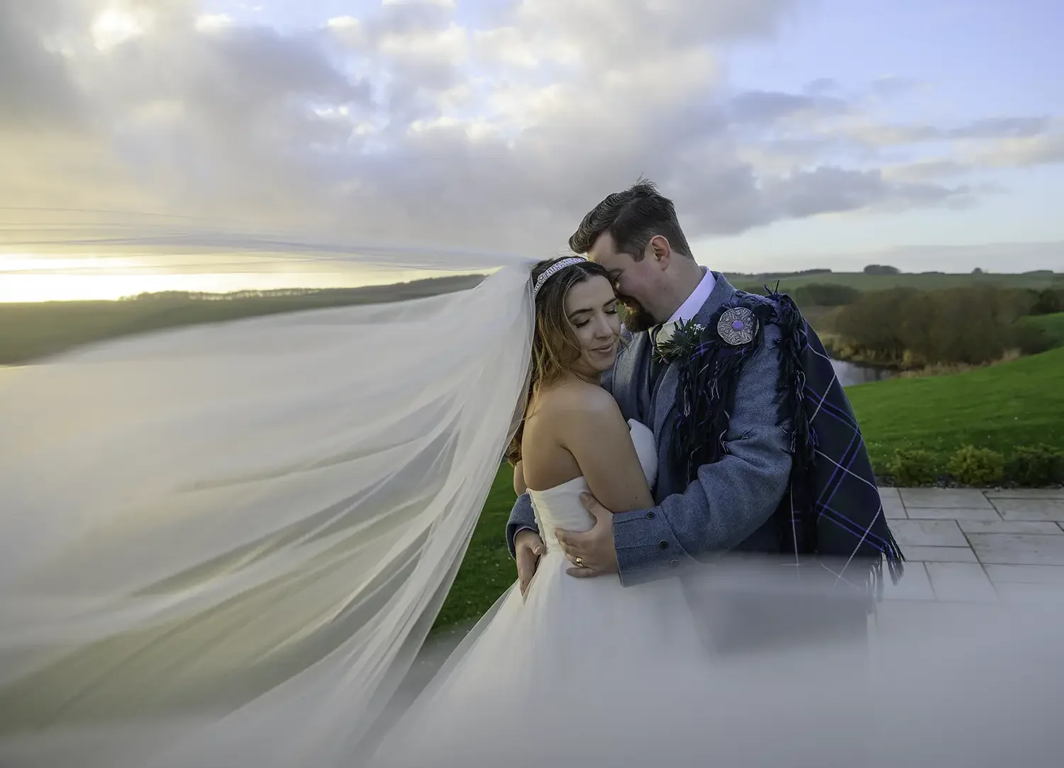 Bride and groom embracing at sunset at Lochside House Hotel in New Cumnock