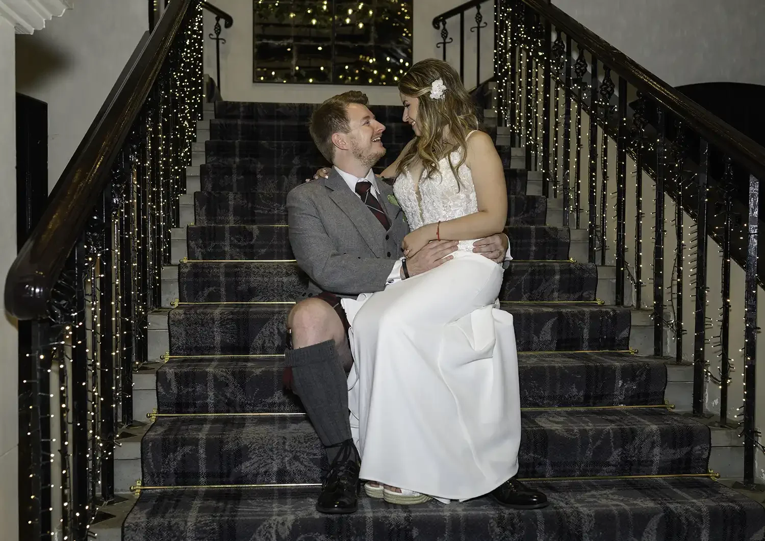 Bride and groom sitting on staircase at Brig o' Doon House Hotel in Alloway, Ayr