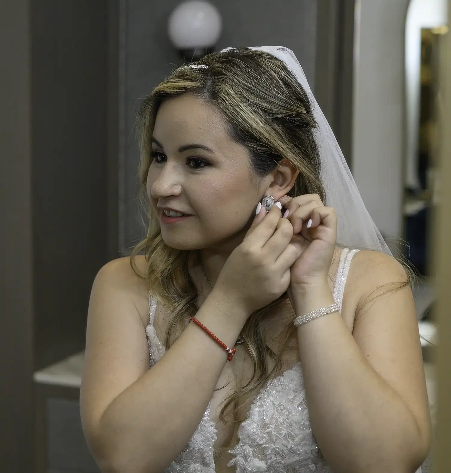 Bride putting on her earrings during bridal preparations at Brig o' Doon House Hotel wedding venue in Alloway, Ayrshire.