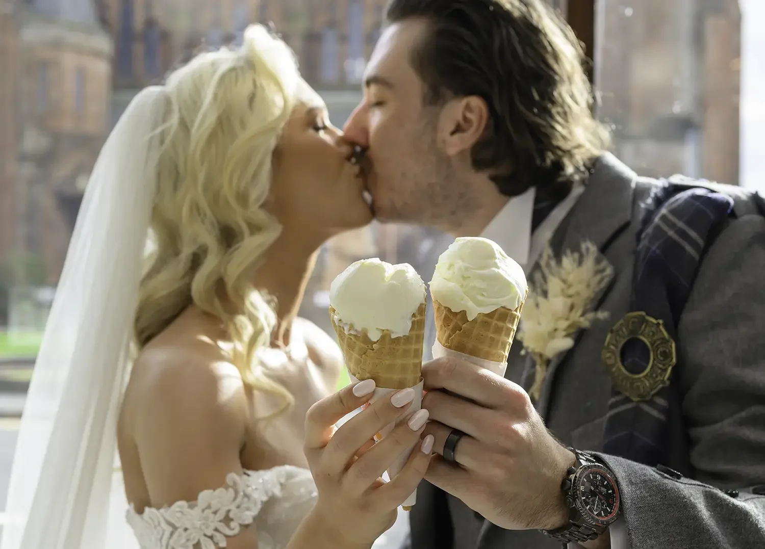 Bride and groom Mia and Ryan sharing a kiss while holding ice cream cones at their Brisbane House Hotel wedding in Largs.