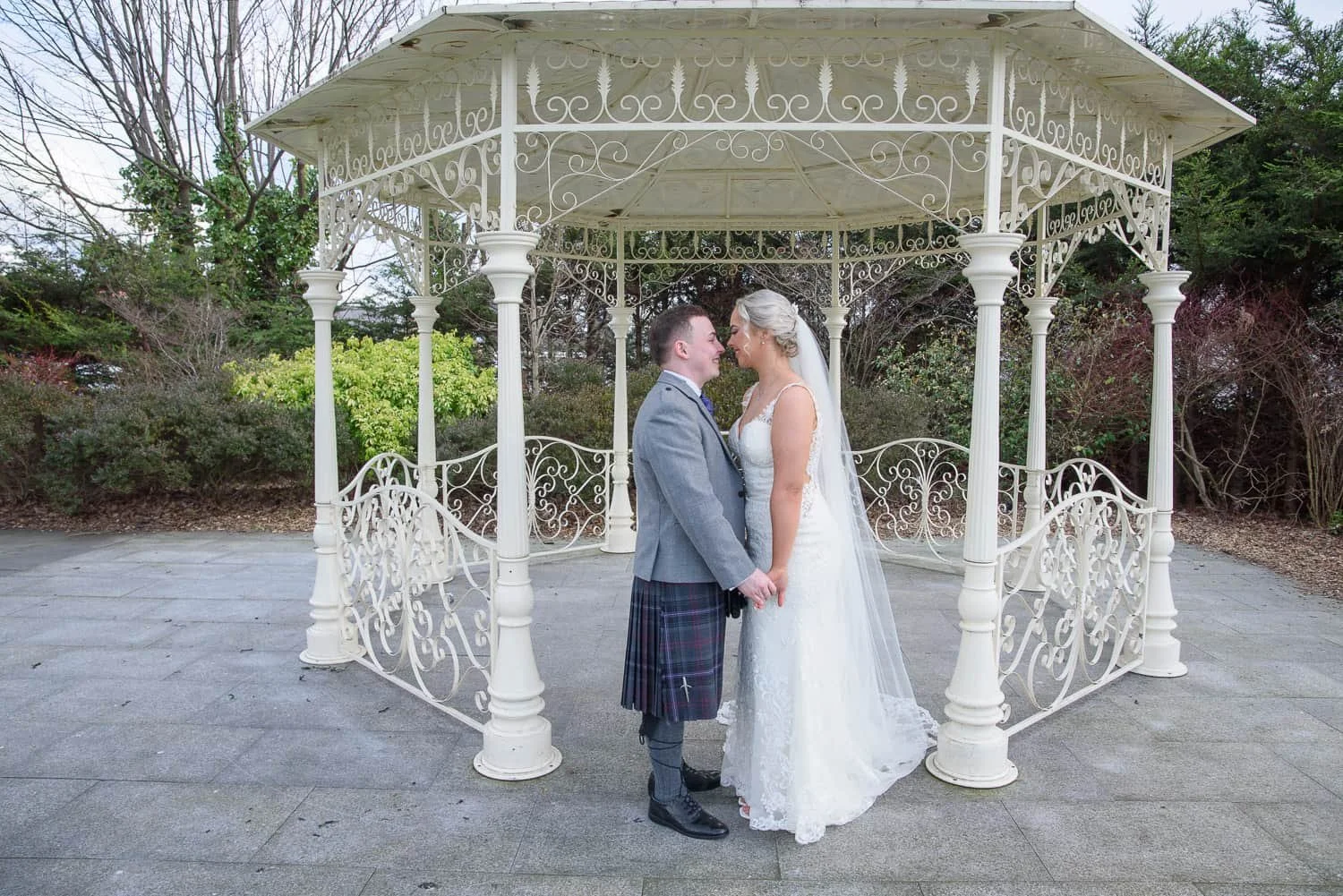 Bride and groom standing together beneath the gazebo at The Carlton Hotel Prestwick