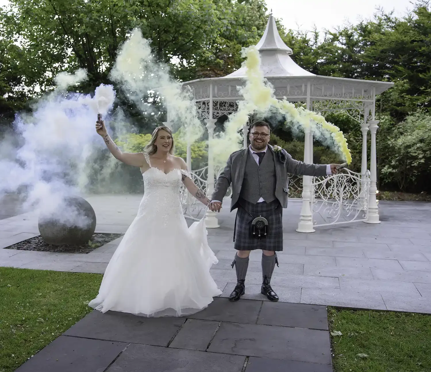 Bride Stacy and groom Darren celebrating with colourful smoke bombs outside the Carlton Hotel in Prestwick on their wedding day