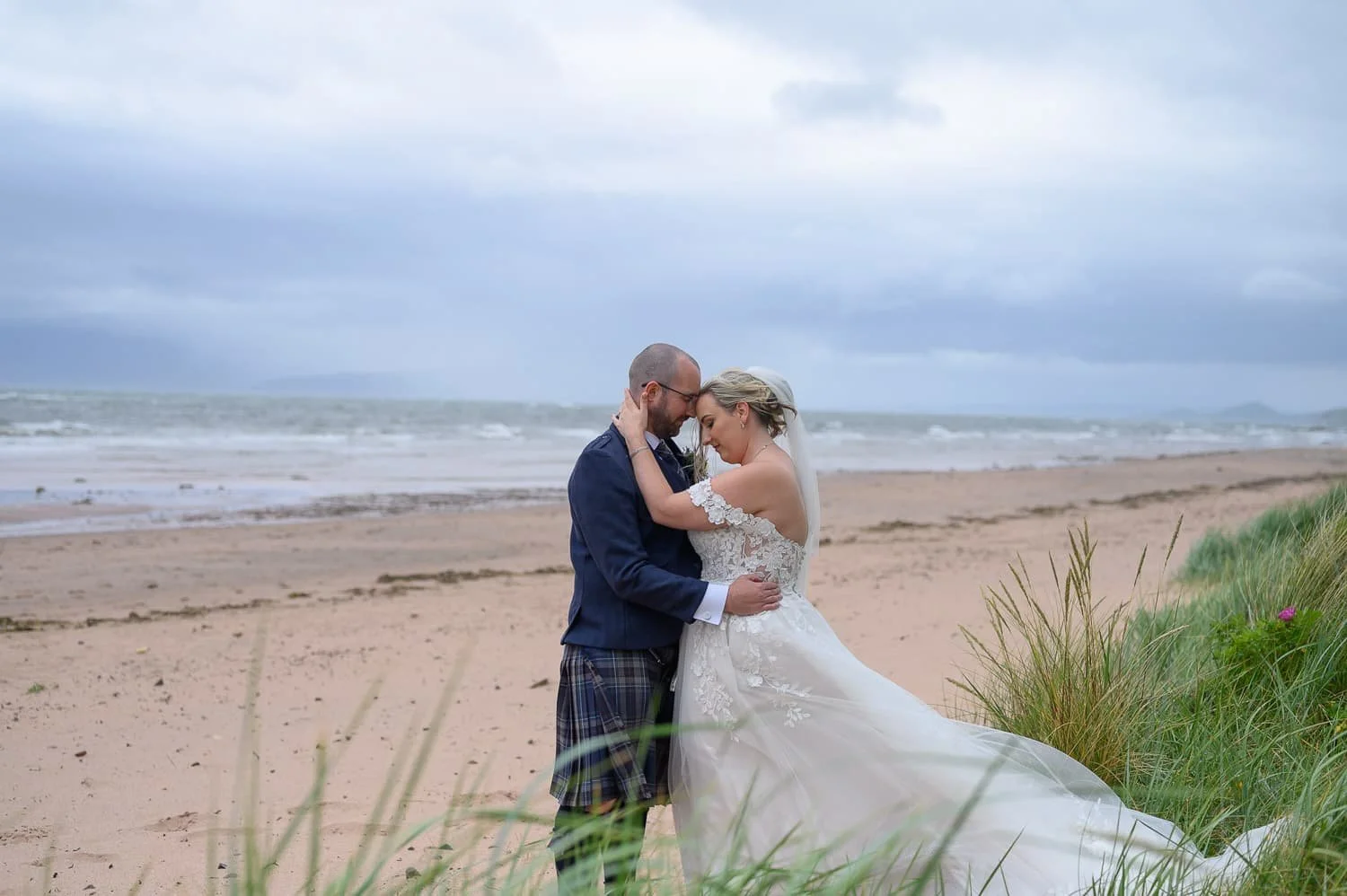 Bride and groom embracing on the beach beside Seamill Hydro Hotel in West Kilbride.