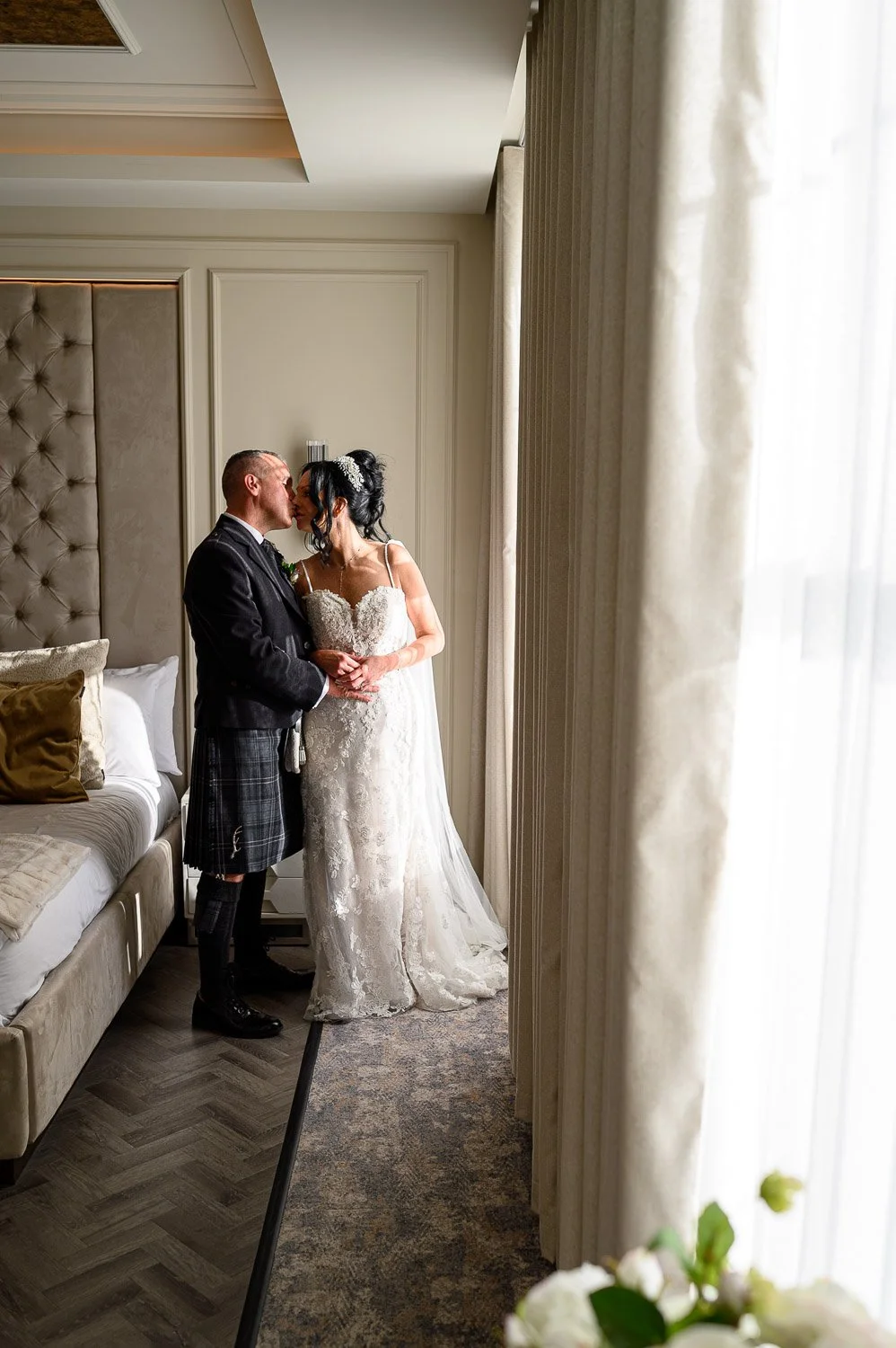 An intimate portrait of a bride and groom kissing by a window in a luxury suite at Brisbane House Hotel.