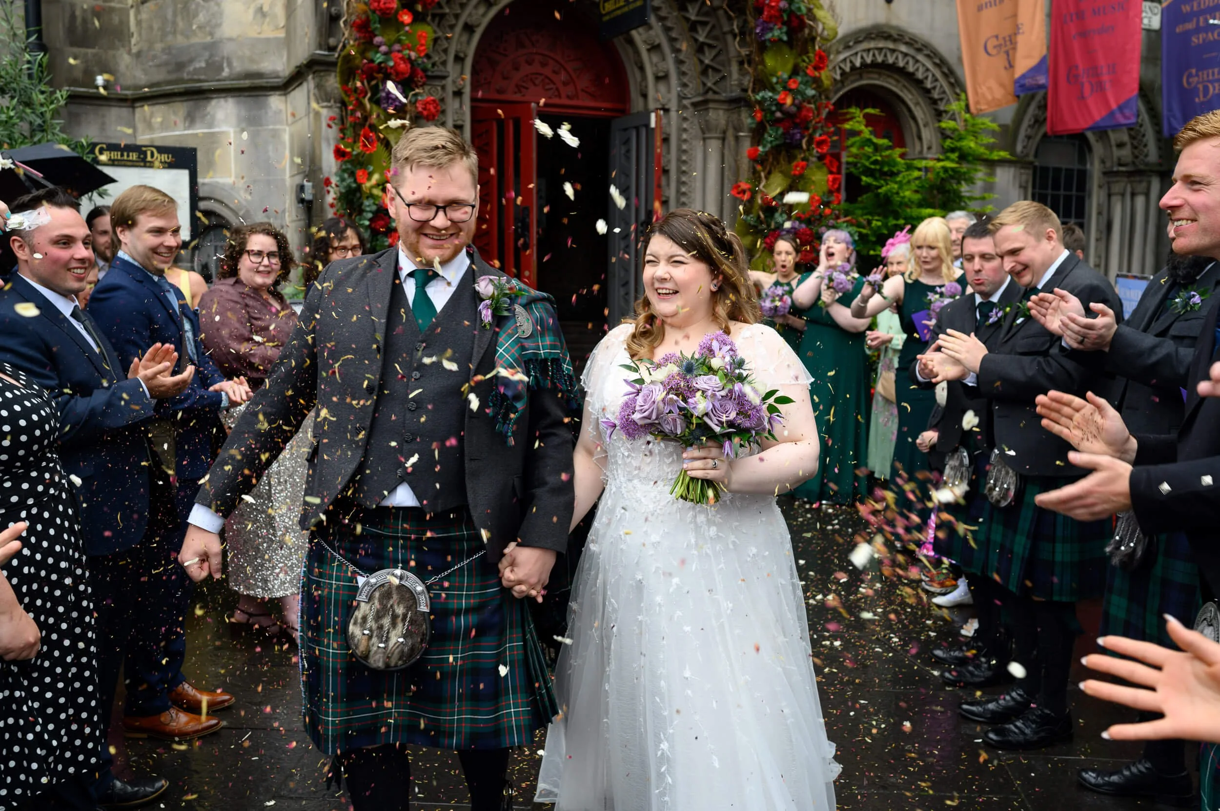 A joyful confetti exit outside The Ghillie Dhu in Edinburgh as the newlyweds walk hand in hand through cheering guests. With colourful petals flying and big smiles all around, this moment perfectly captures the energy and celebration of a Scottish ci