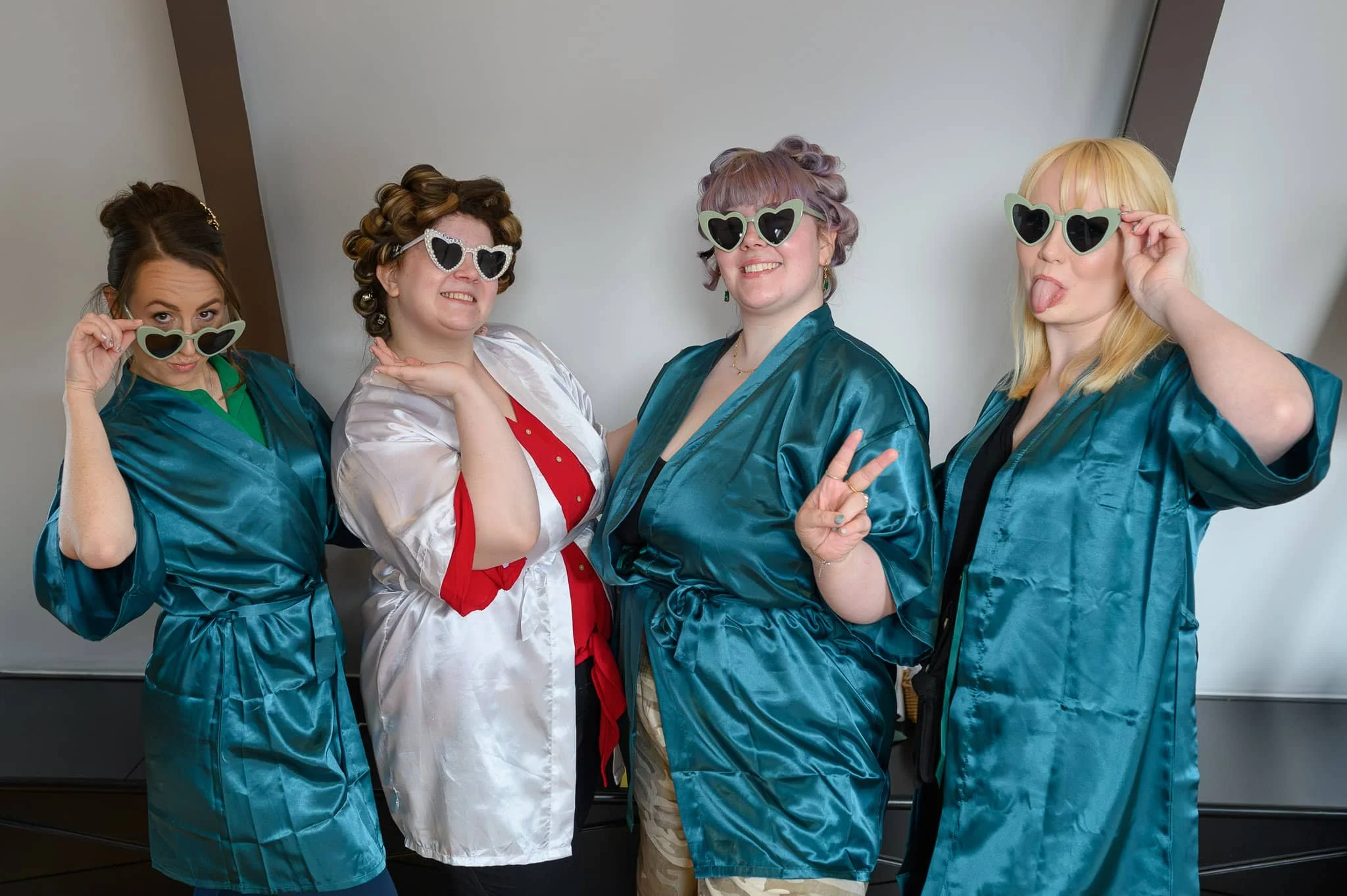 Bridesmaids wearing satin robes and heart sunglasses during wedding morning preparations in North Bridge, Edinburgh.