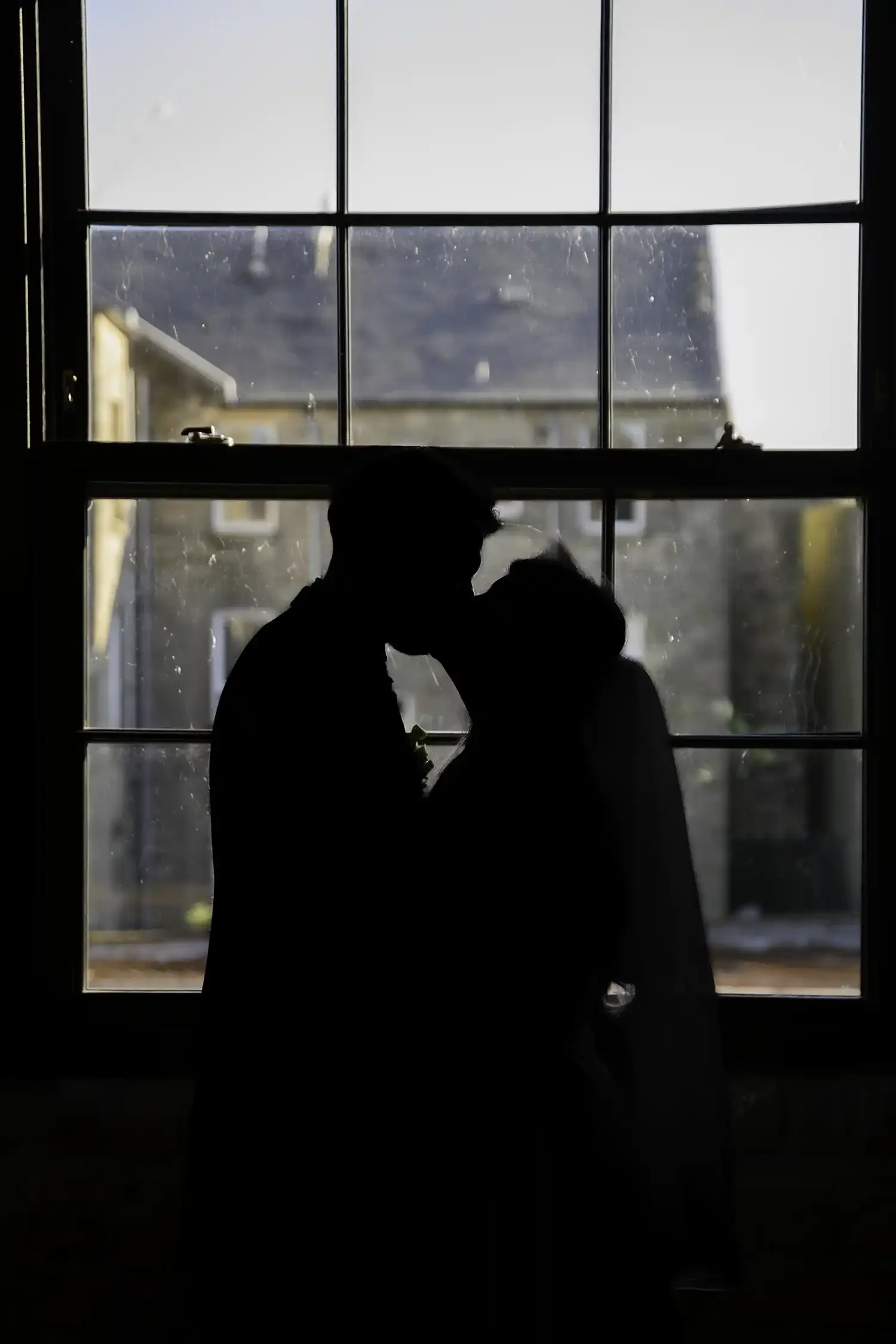 Silhouette of bride and groom kissing in front of window at The Engine Works in Glasgow