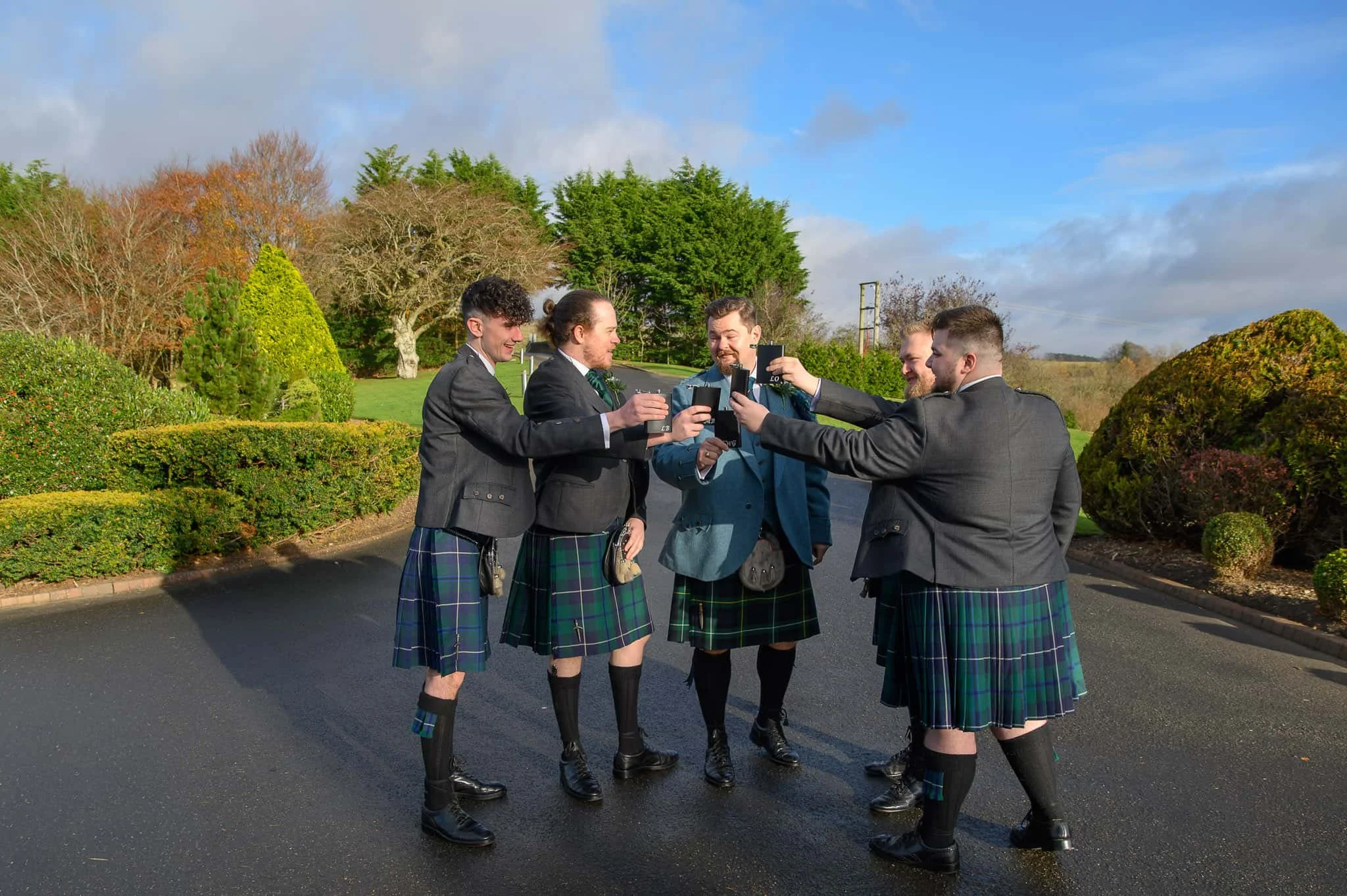 Groom and groomsmen sharing a toast outside Lochside House Hotel in New Cumnock before the wedding ceremony