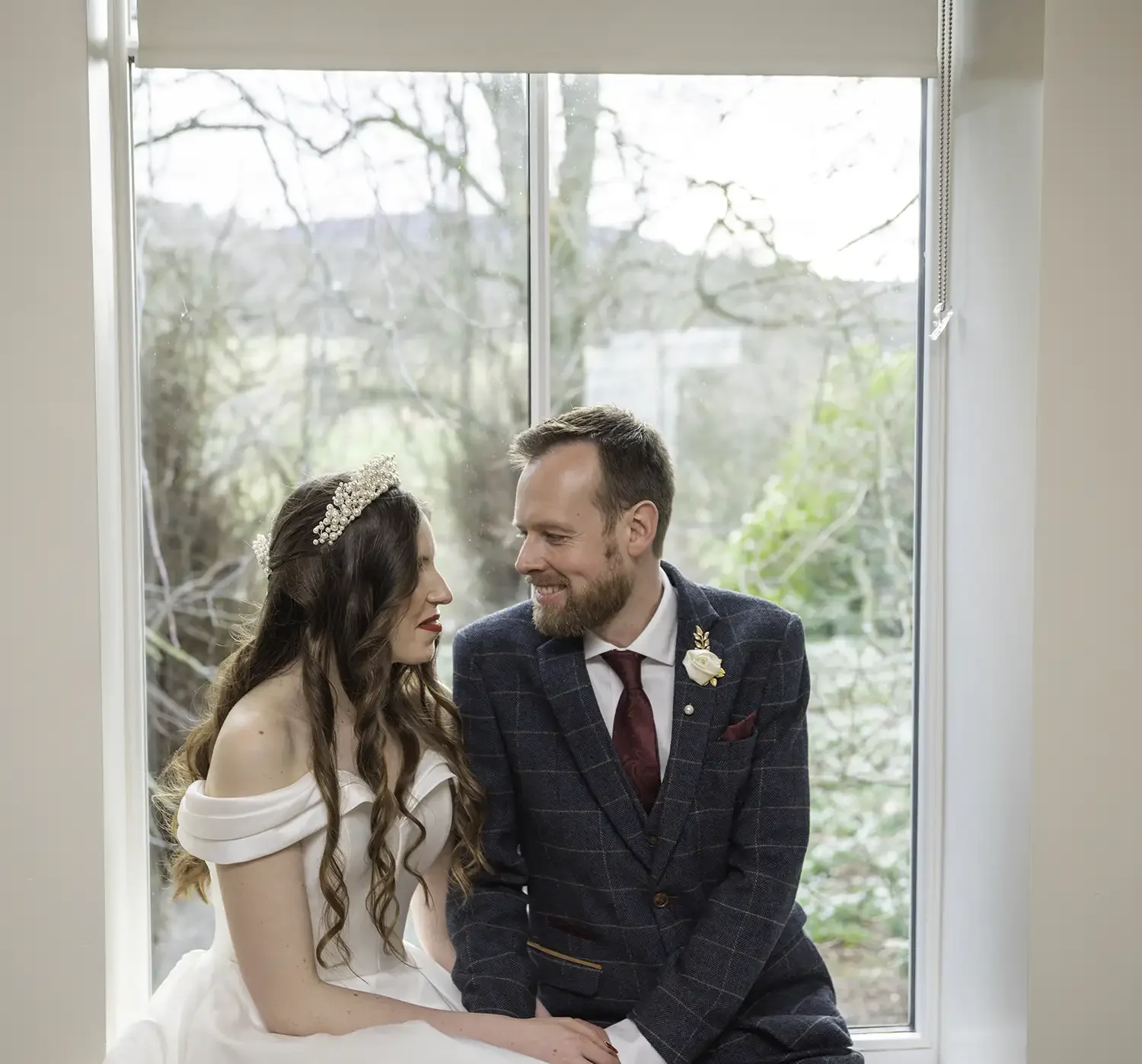 Bride Brogan and groom Lance sitting together by a window at Logie Country House in Inverurie on their wedding day