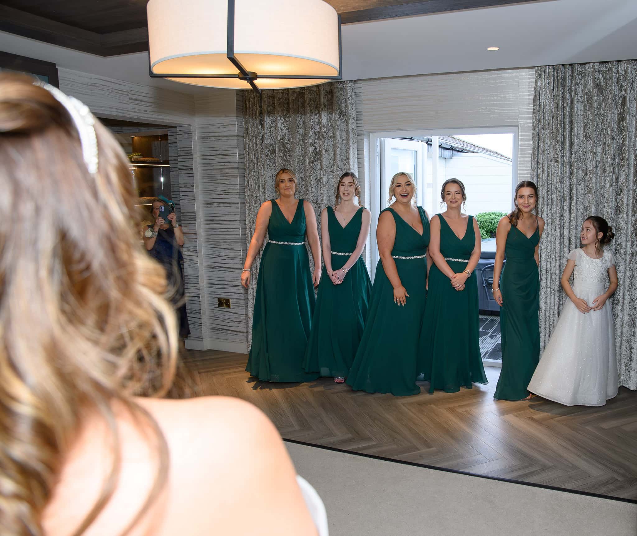 Bridesmaids reacting as they see the bride in her wedding dress during morning preparations at Lochside House Hotel in New Cumnock