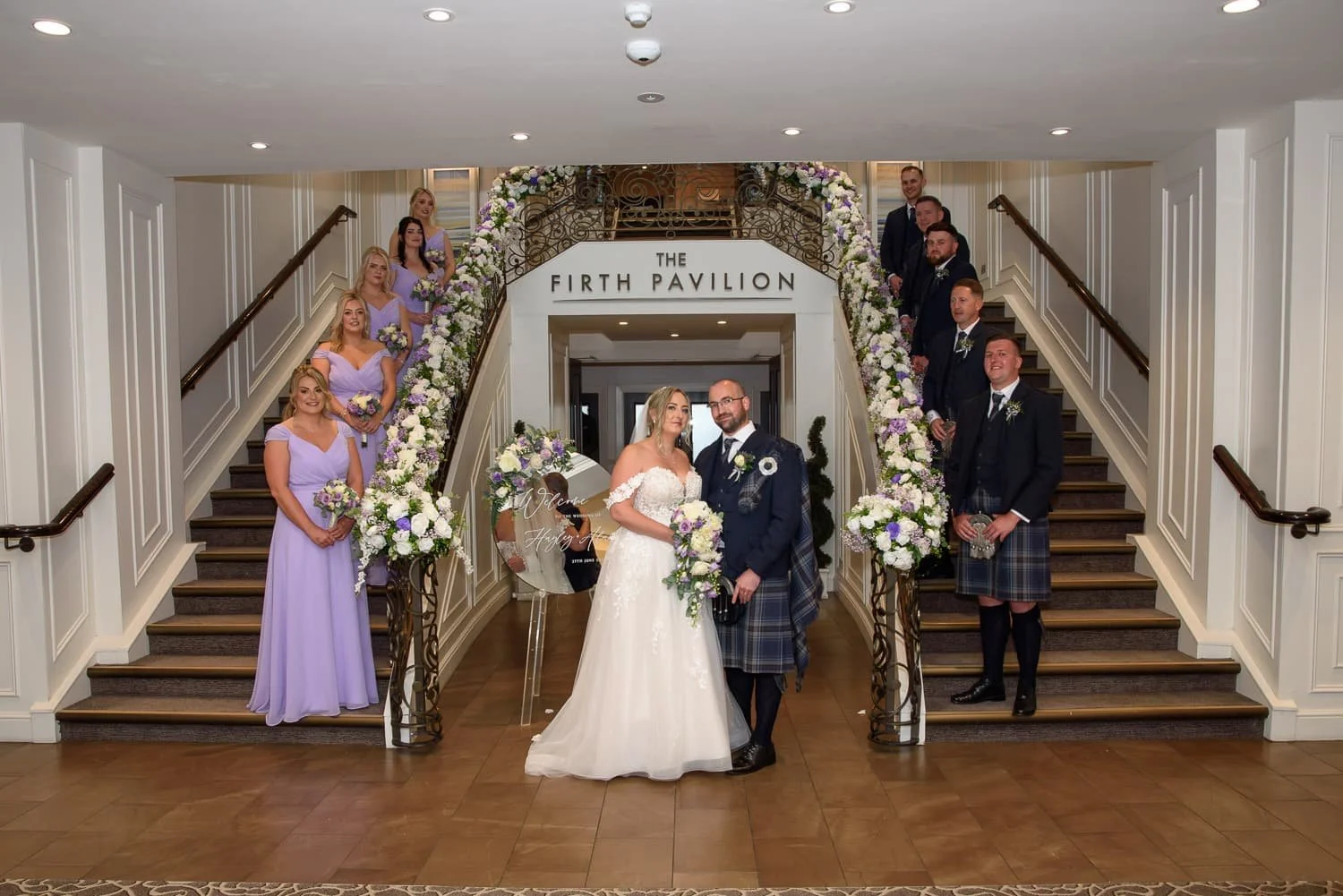 Bride and groom with bridesmaids and groomsmen on the staircase at the Firth Pavilion inside Seamill Hydro Hotel.
