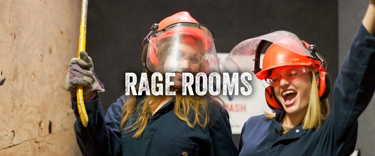 Two girls pose with arms raised, smiling widely, after smashing breakables in the rage room. 