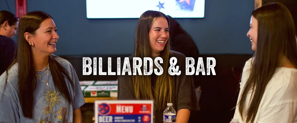 Group of young ladies socialize at bar table with drinks and snacks. 