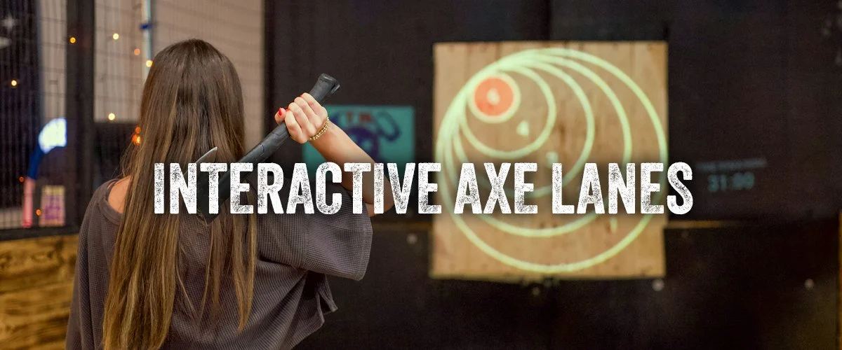 Girl throws axe at the bullseye in our interactive axe throwing lanes.