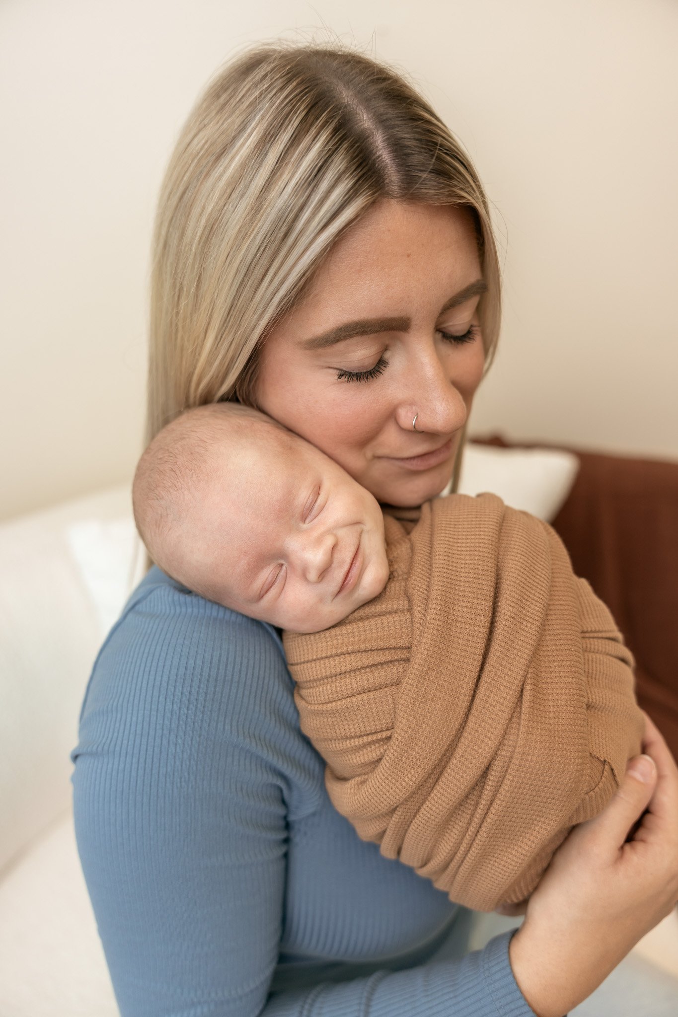 Mother cuddling a sleeping newborn baby indoors
