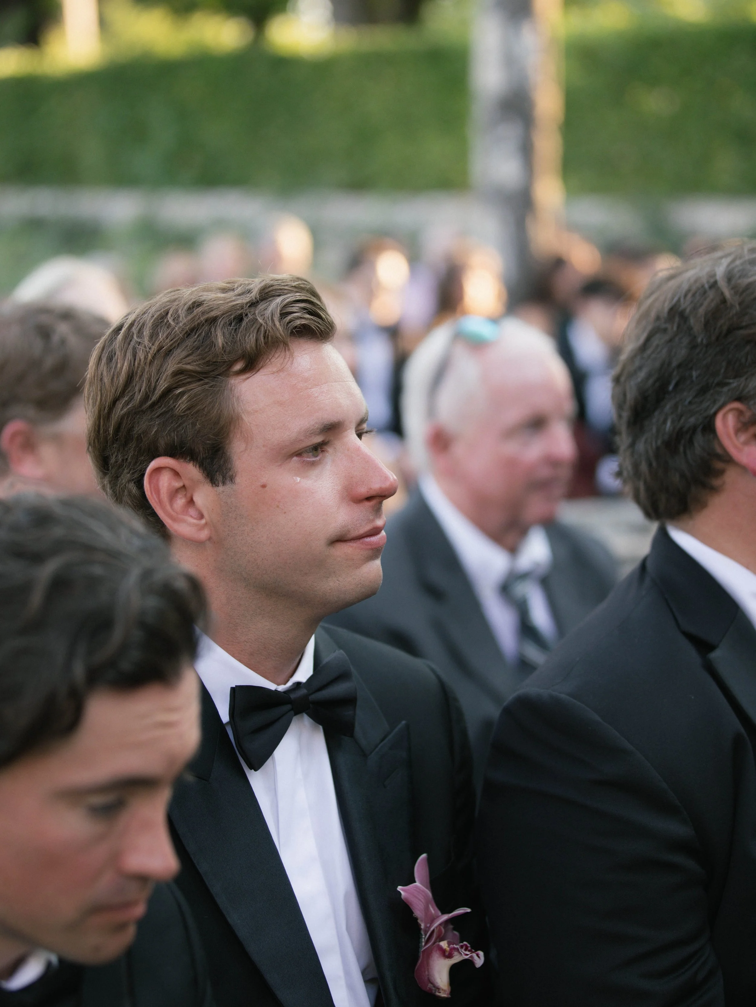Young men dressed in tuxedos attending a formal event, sitting outdoors. Villa Cimbrone wedding Amalfi Coast