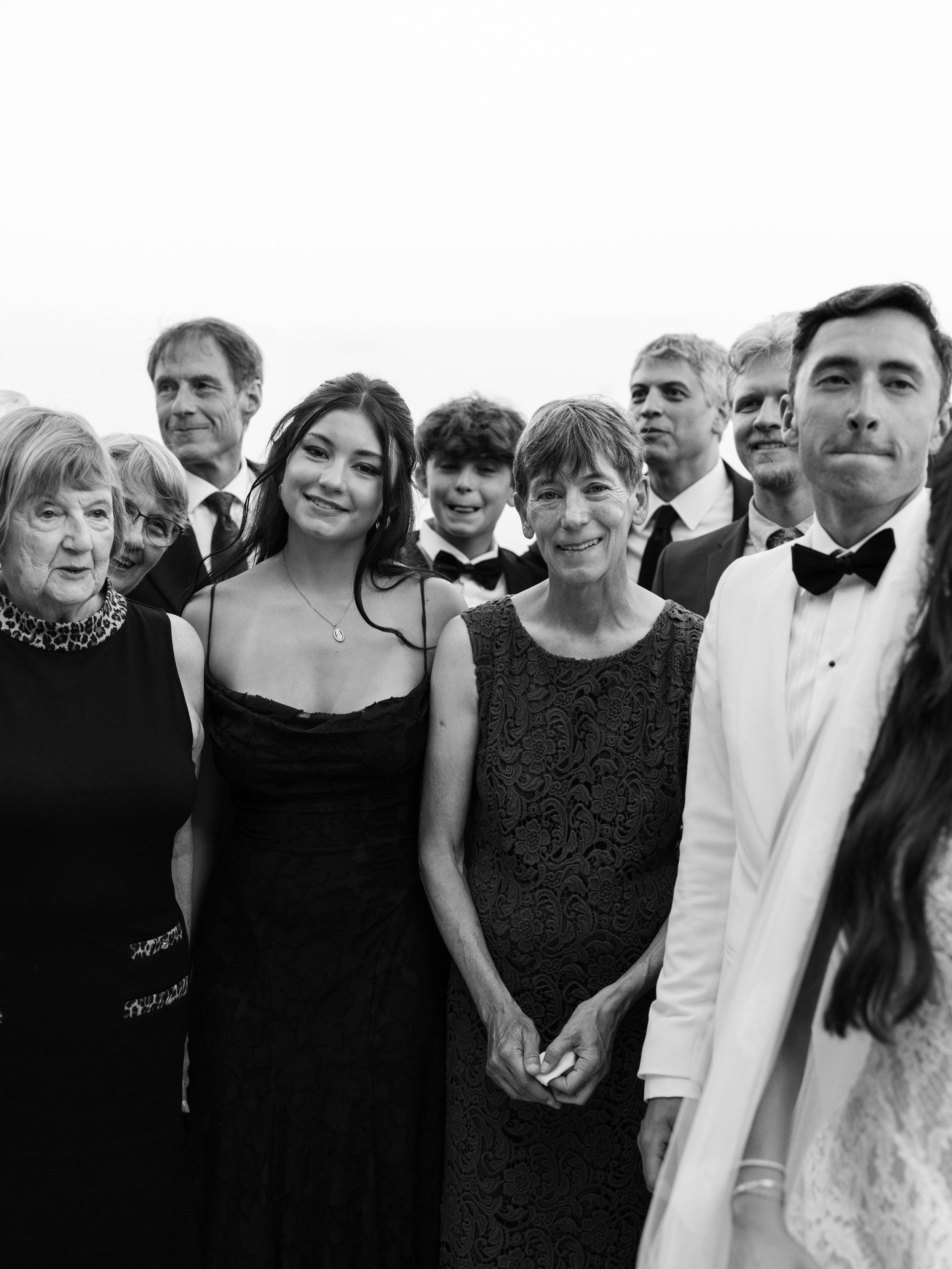 A group of people dressed formally, holding hands, and standing closely together at what appears to be a celebration or event.  Villa Cimbrone wedding Amalfi Coast Ravello Infinity Terrace
