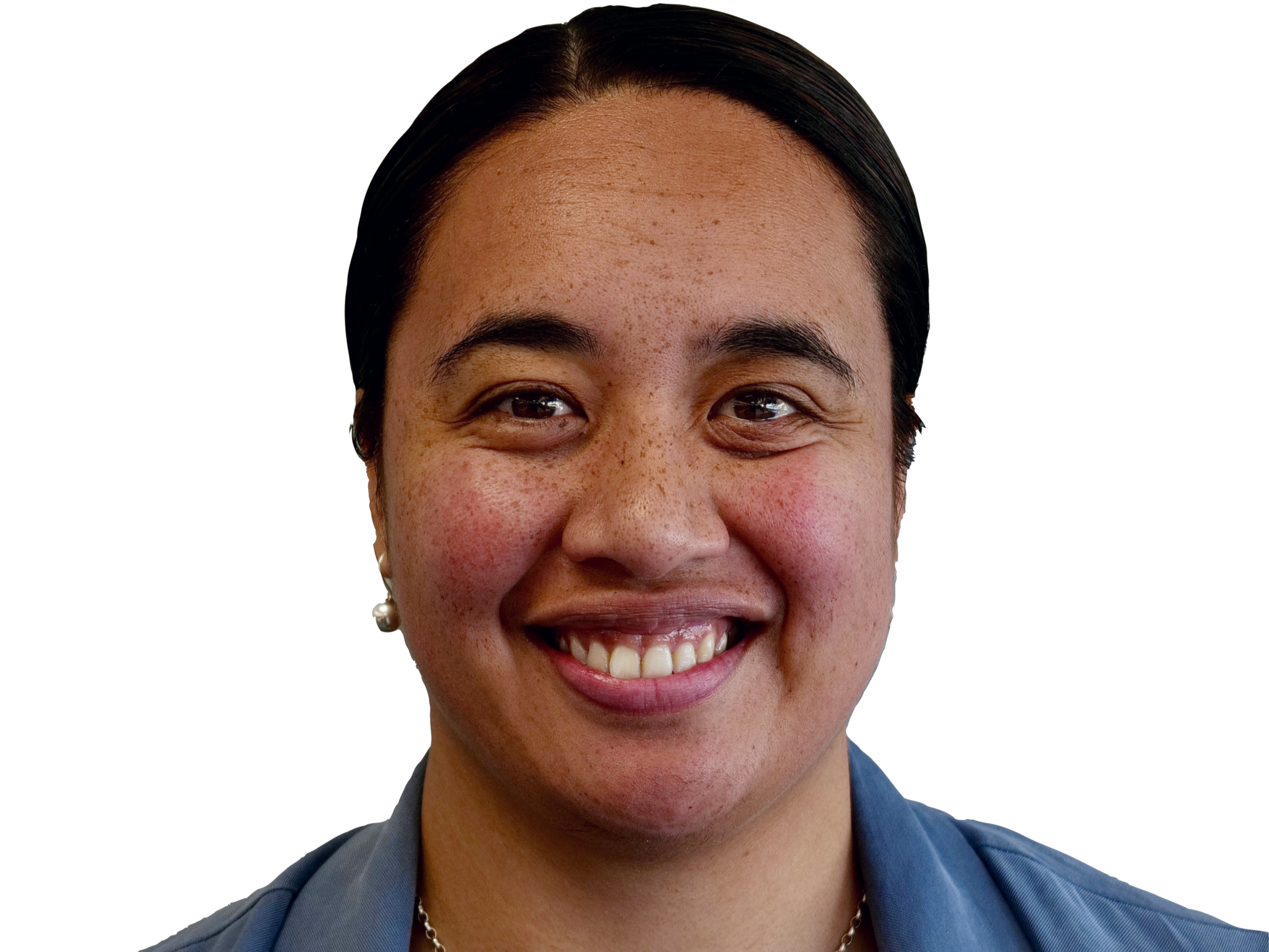 A woman with dark hair, brown eyes, and a broad smile showing her teeth, wearing pearl earrings and a necklace, against a black background.