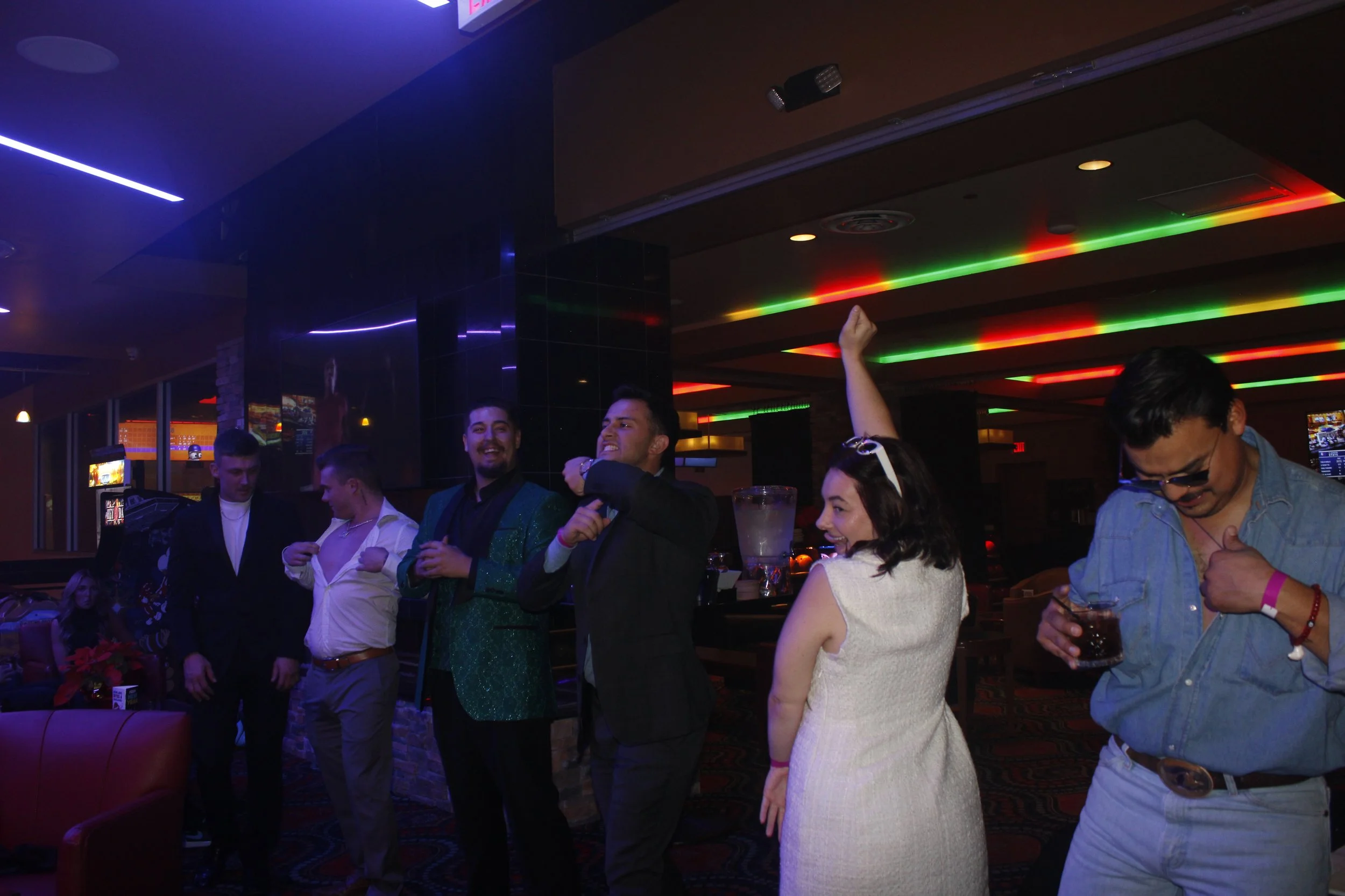 People dancing and having a good time in a nightclub with colorful neon lights.