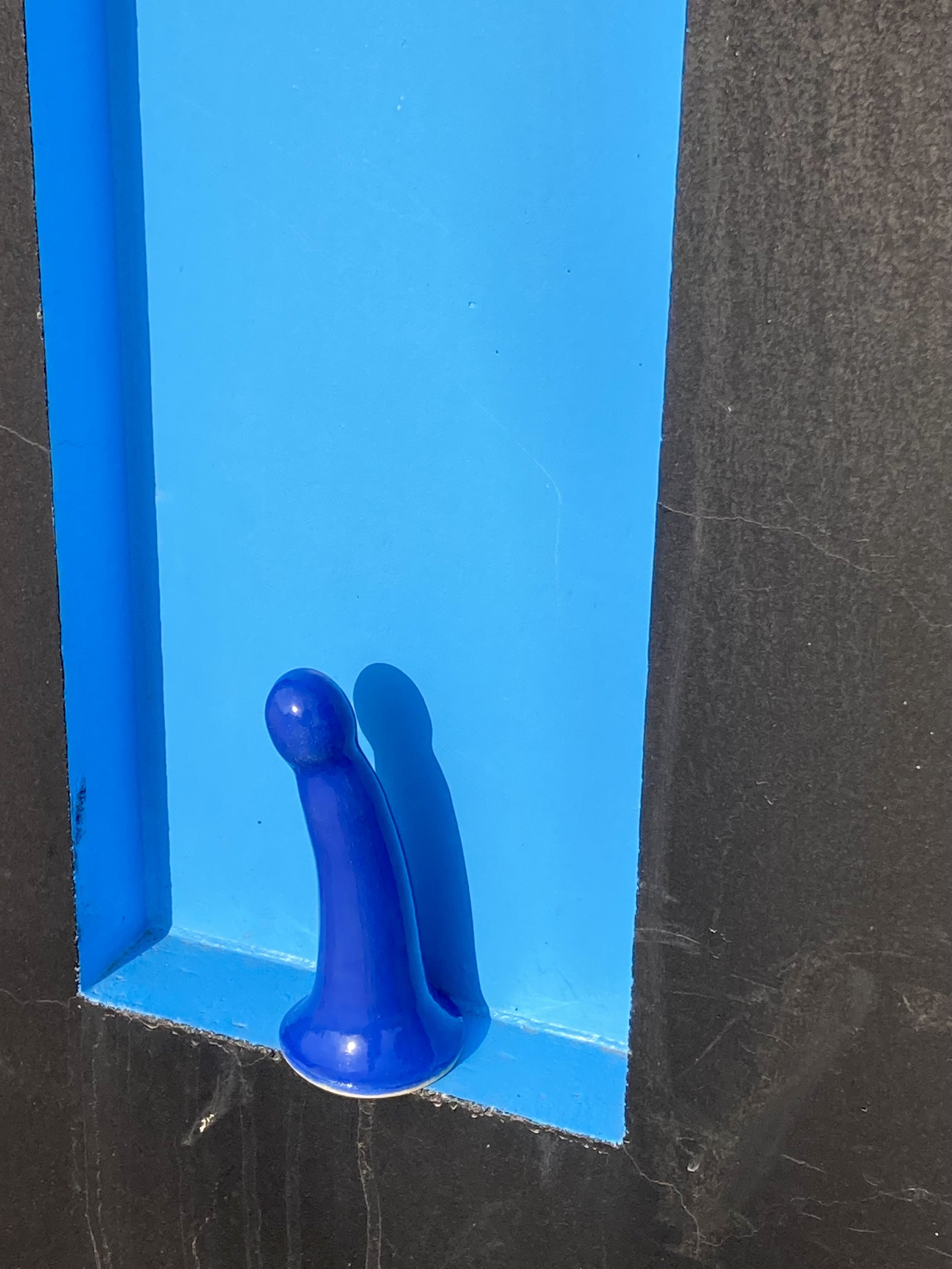 Blue curved ceramic dildo blue background