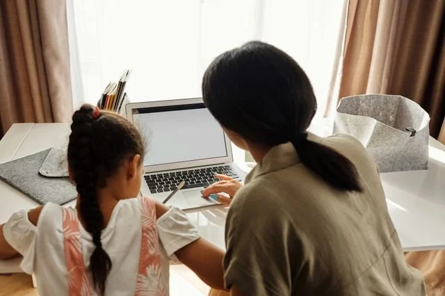 Mom helping child at computer