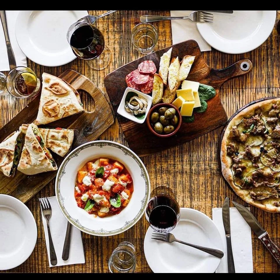 A table of shared dishes, pizza, pasta and wine at Edo Cucina.