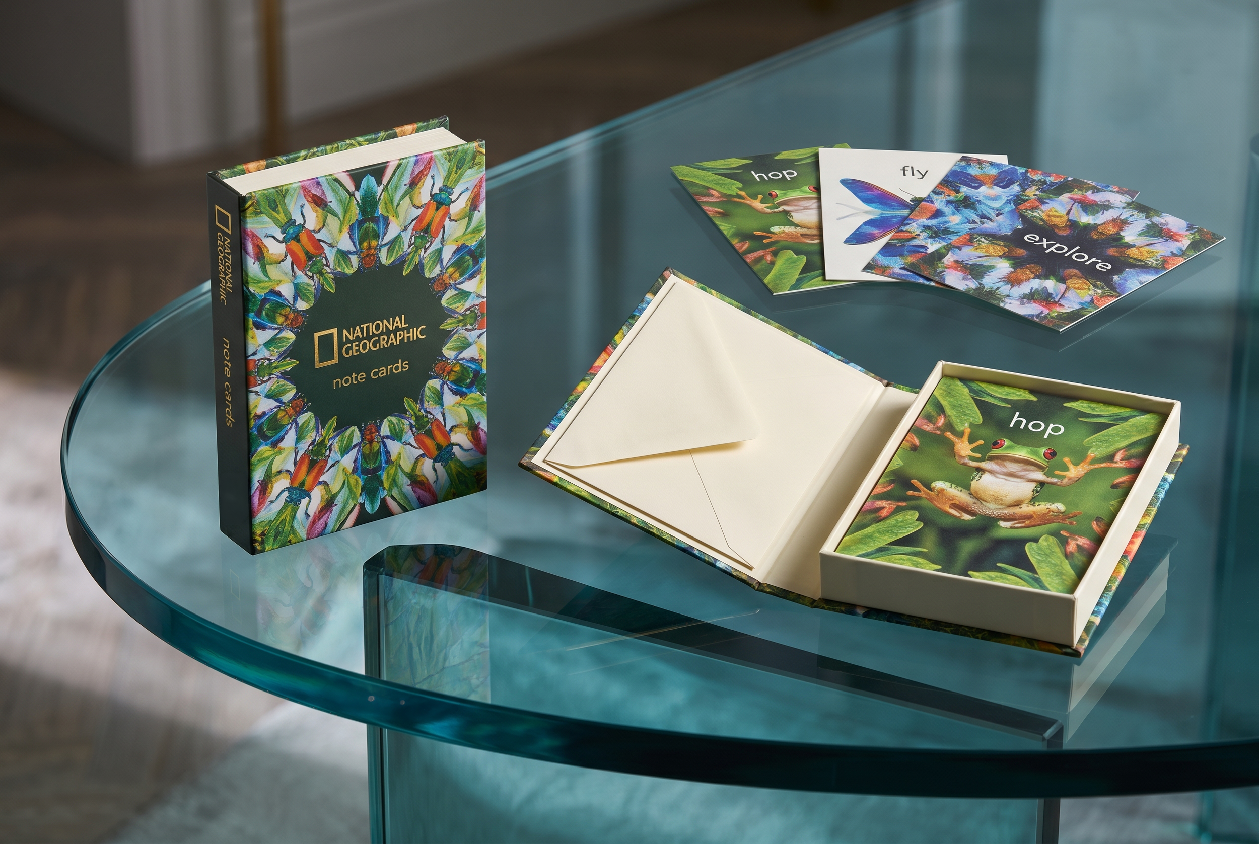 A keepsake‑style box designed to open like a bound volume, containing a series of art note cards and envelopes featuring rainforest insects and amphibians. Each pattern is created through a kaleidoscopic reinterpretation of imagery sourced from the N