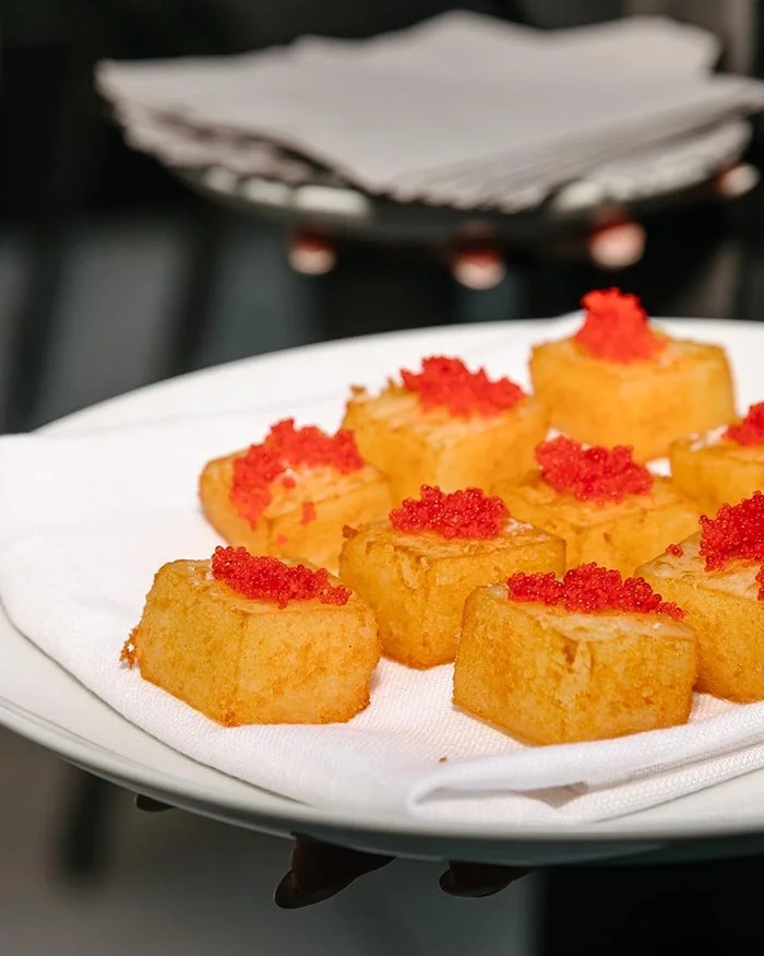 Close-up of bite-sized square appetizers arranged on a white plate