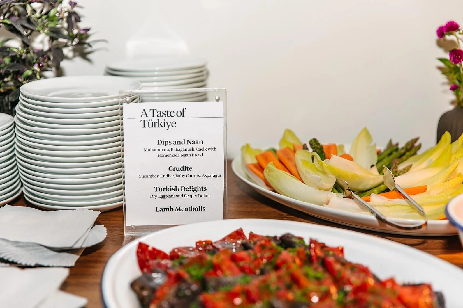 Printed menu displayed on a table next to plated dishes and stacked dinner plates