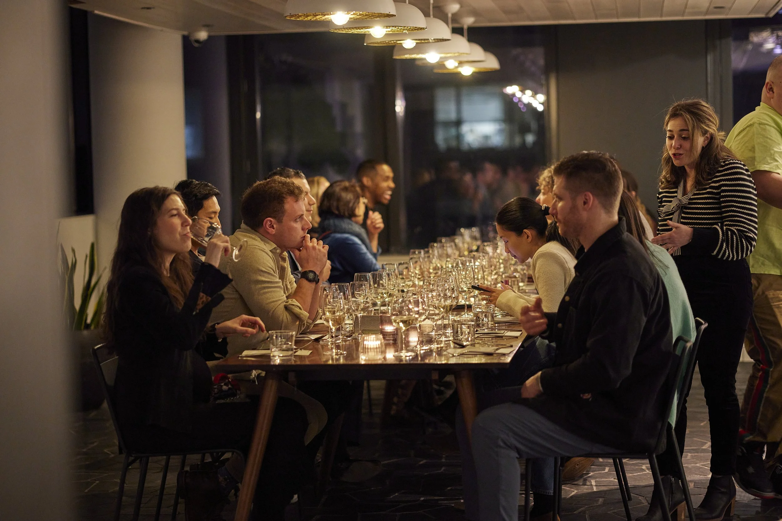 Group of diners seated at an elegant private dining experience with shared table, wine glasses, and intimate lighting