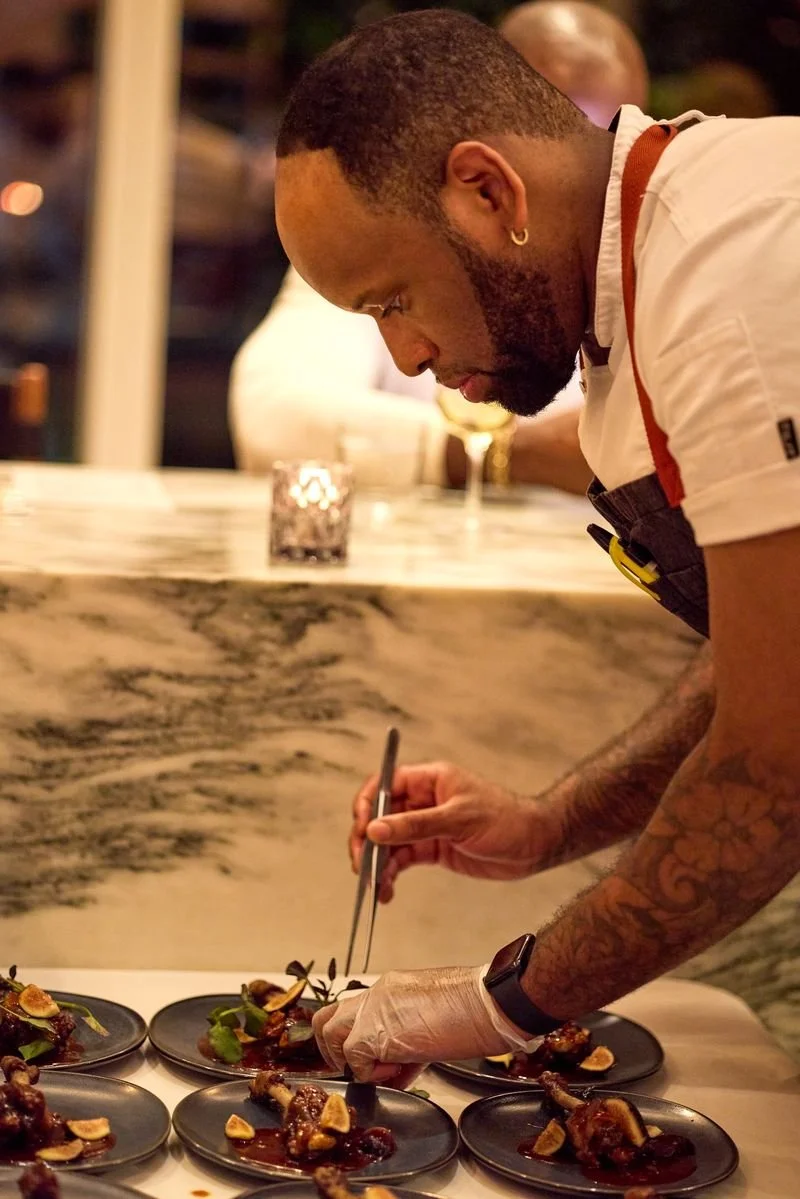 Chef leaning over a counter while arranging food on small plates